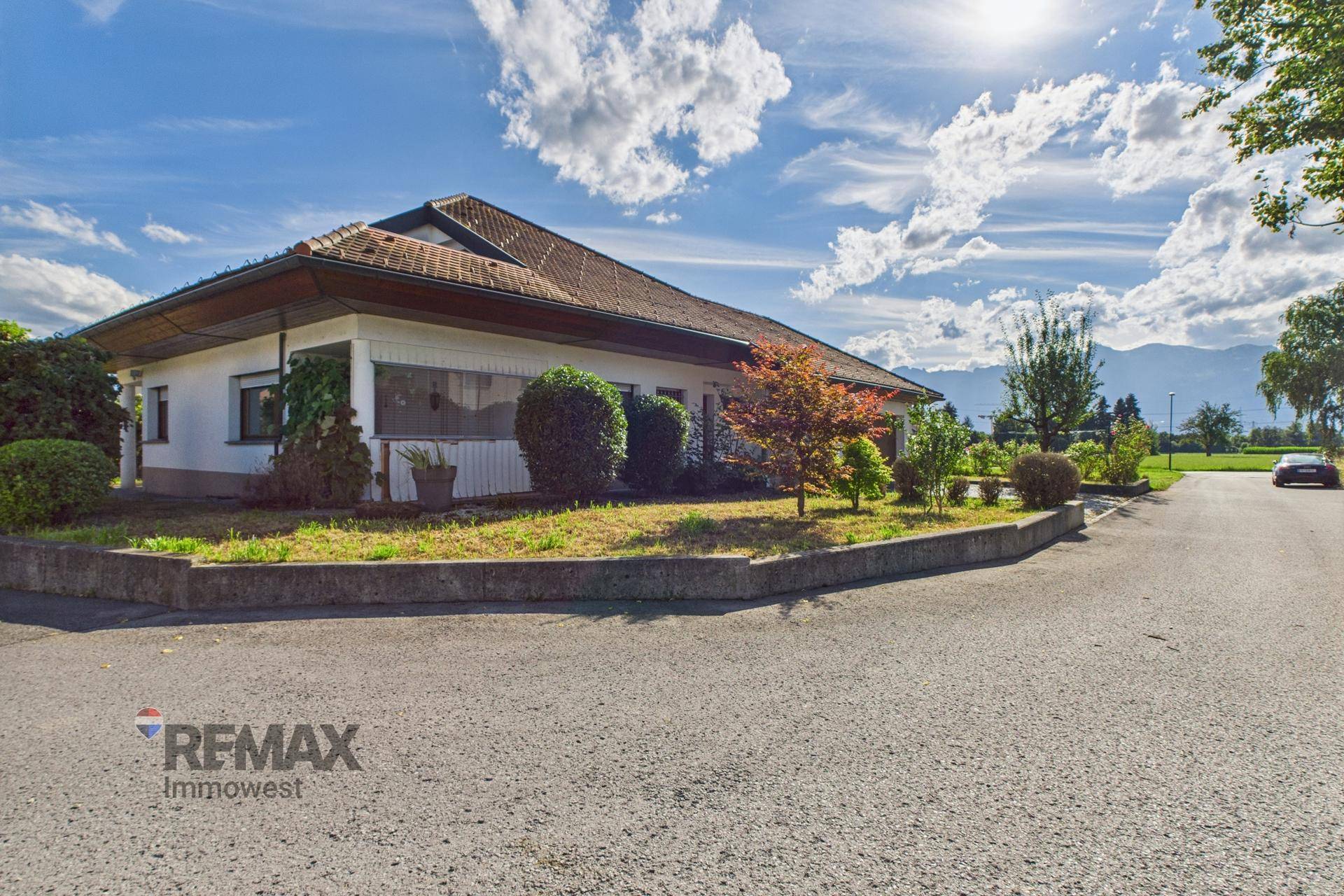 Weitläufige Ansicht des Hauses mit gepflegtem Vorgarten und Bergblick im Hintergrund.