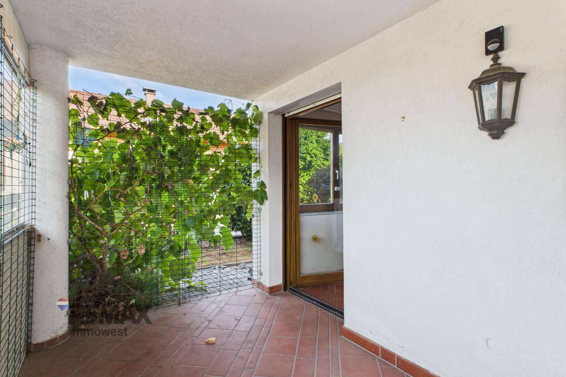 Überdachte Loggia mit Terrakottafliesen und begrünten Wänden, ideal zum Entspannen.