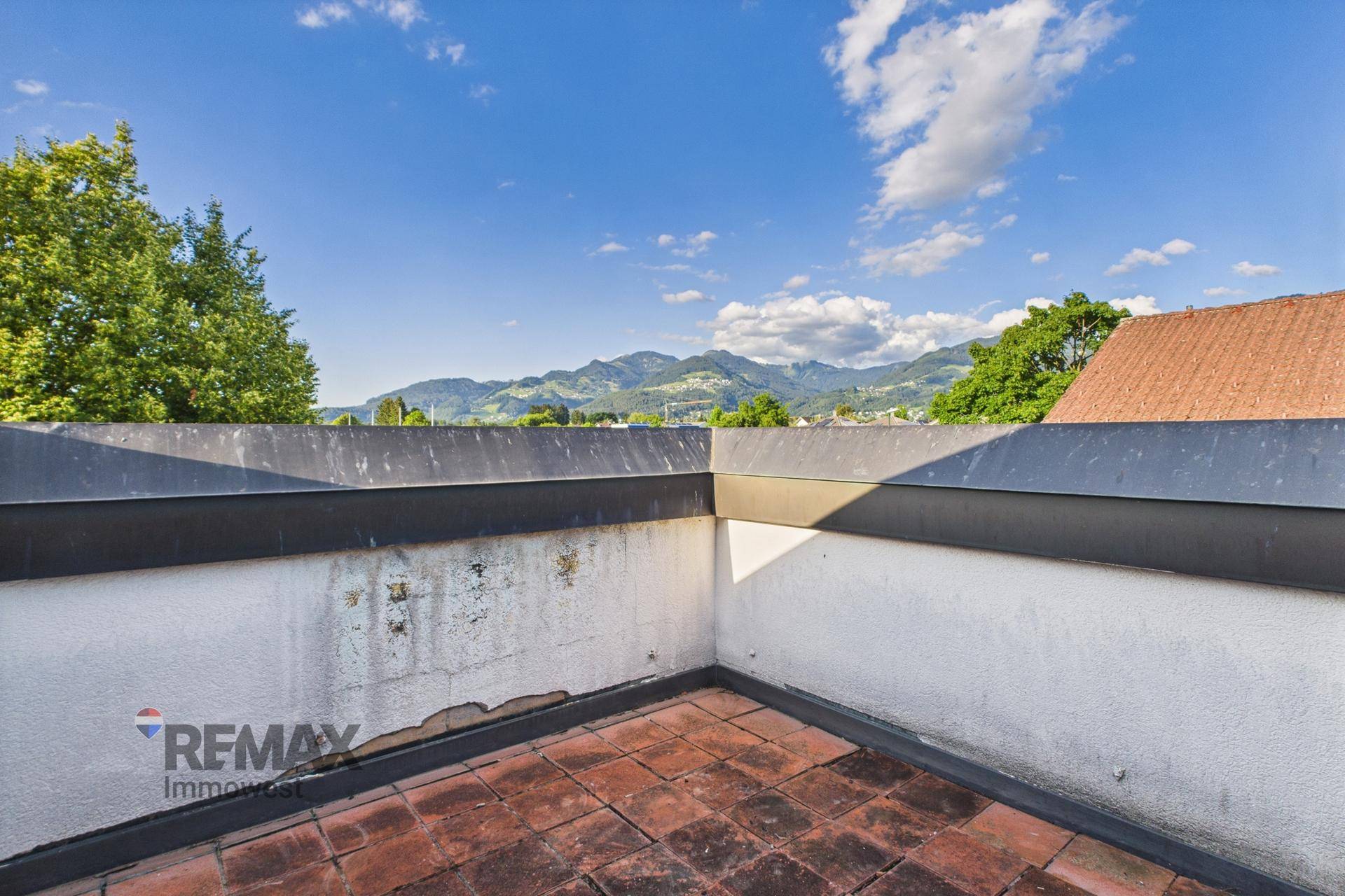 Dachterrasse mit Bergblick und Ziegelboden, ideal für sonnige Stunden im Freien.