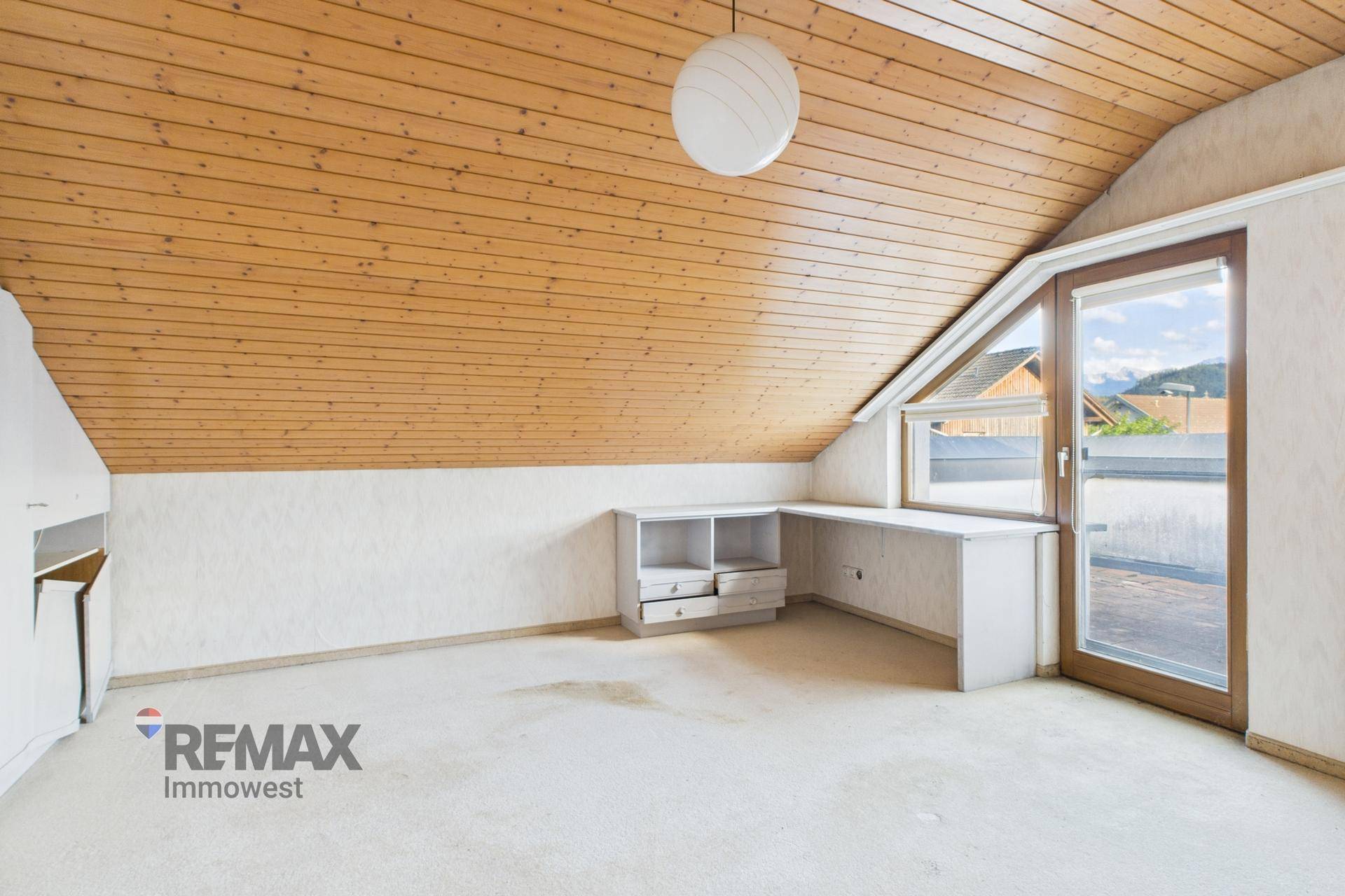 Helles Dachzimmer mit Holzdecke, integriertem Schreibtisch und Zugang zur Dachterrasse.