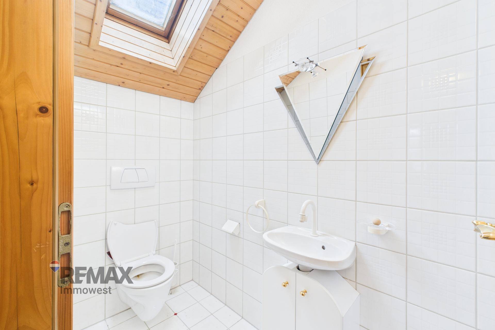 Kleines Gäste-WC mit Wand-WC, Waschbecken und Dachfenster für natürliche Belüftung.