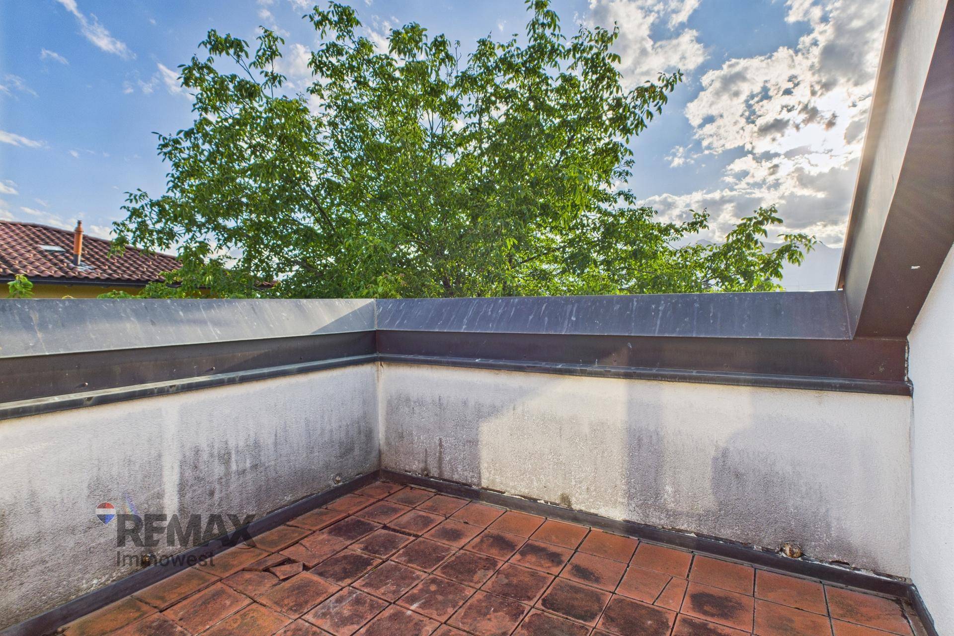 Kleine geflieste Terrasse im Dachgeschoss mit Blick ins Grüne und viel Potenzial zur Gestaltung.