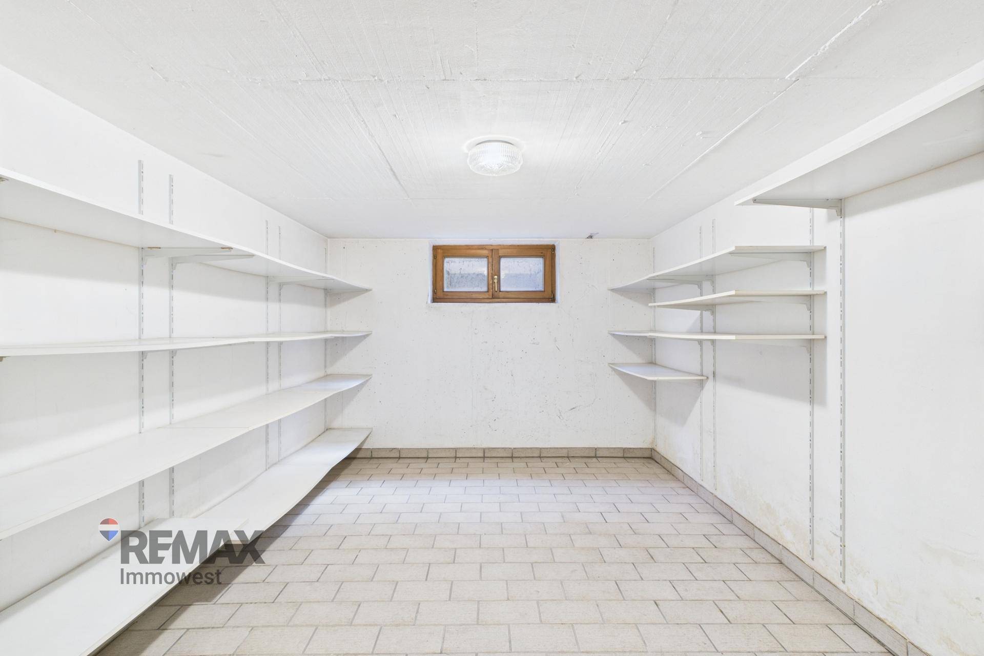 Geräumiger Kellerraum mit umfangreichen Regalsystemen und Fliesenboden für Lagerzwecke.