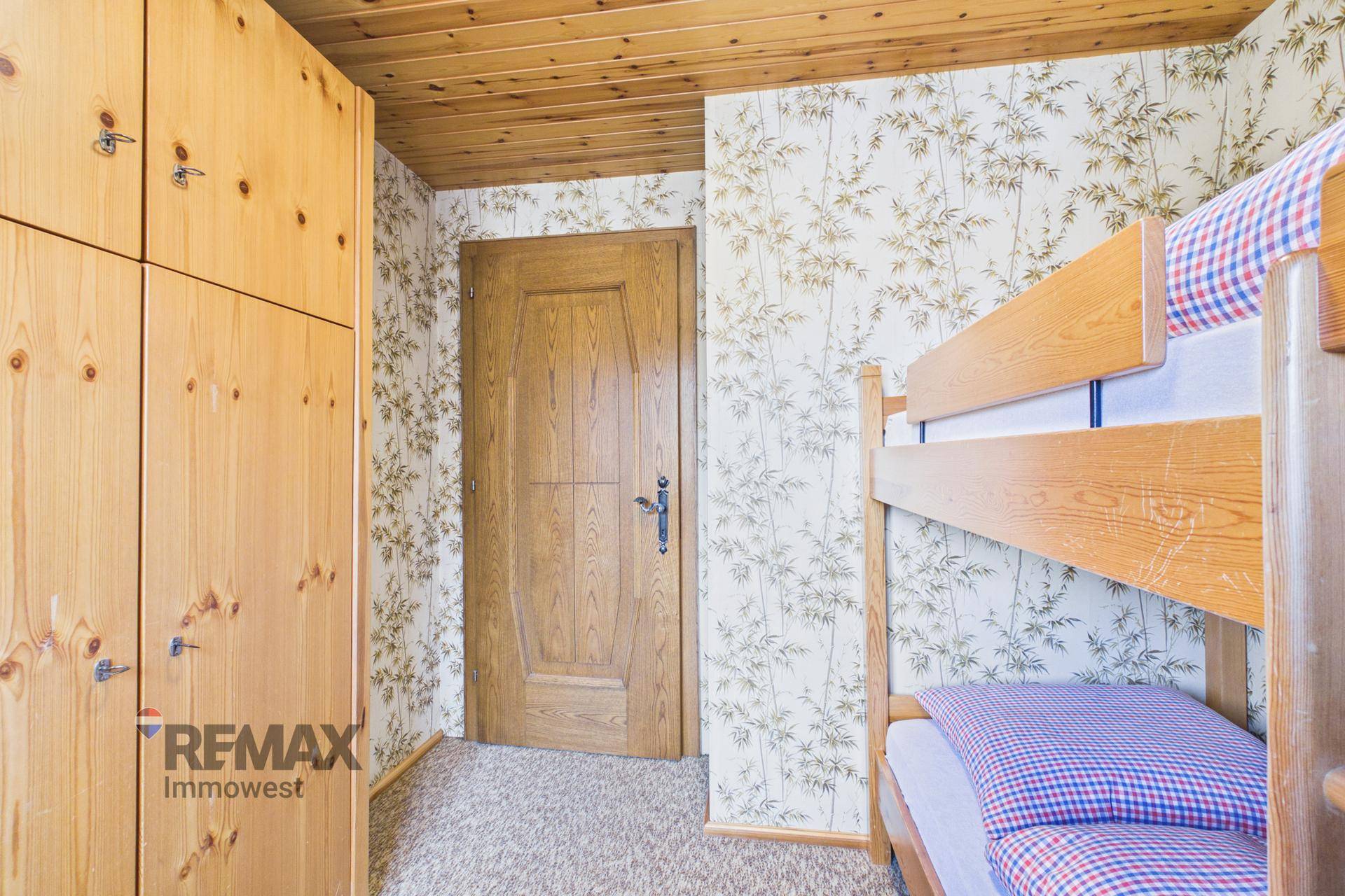 Schlafzimmer mit Etagenbett, Holzschrank und Holztür in rustikalem Stil.