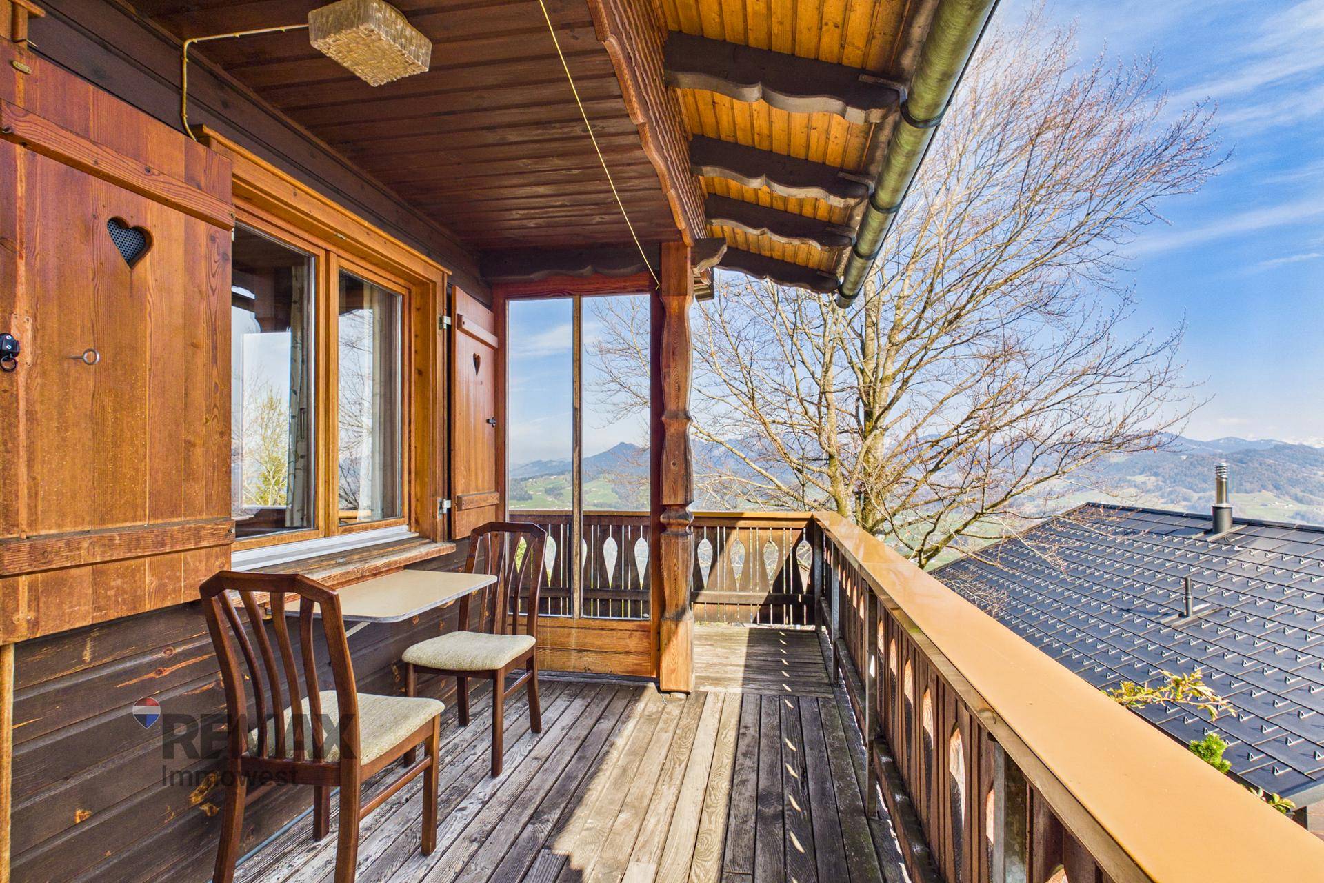 Gemütlicher Holzbalkon mit Sitzgelegenheiten und weitem Blick auf die Bergwelt.
