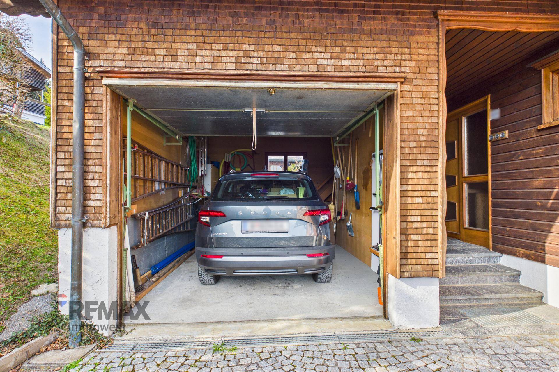 Geräumige Garage mit einem geparkten Auto und Stauraum für Werkzeuge.