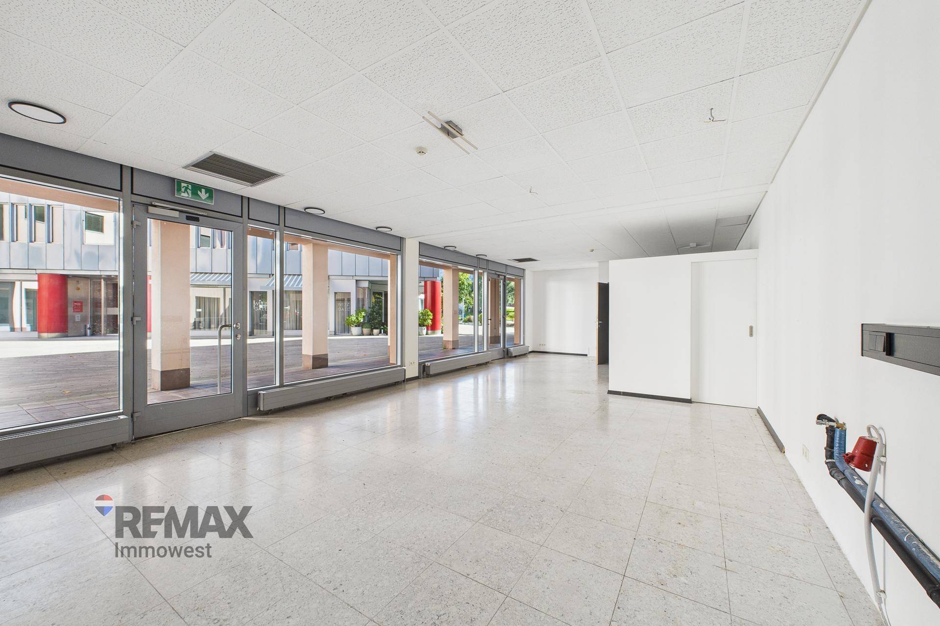 Heller Gewerberaum mit großen Fensterfronten, die viel Tageslicht hereinlassen und einen Blick nach draußen bieten.