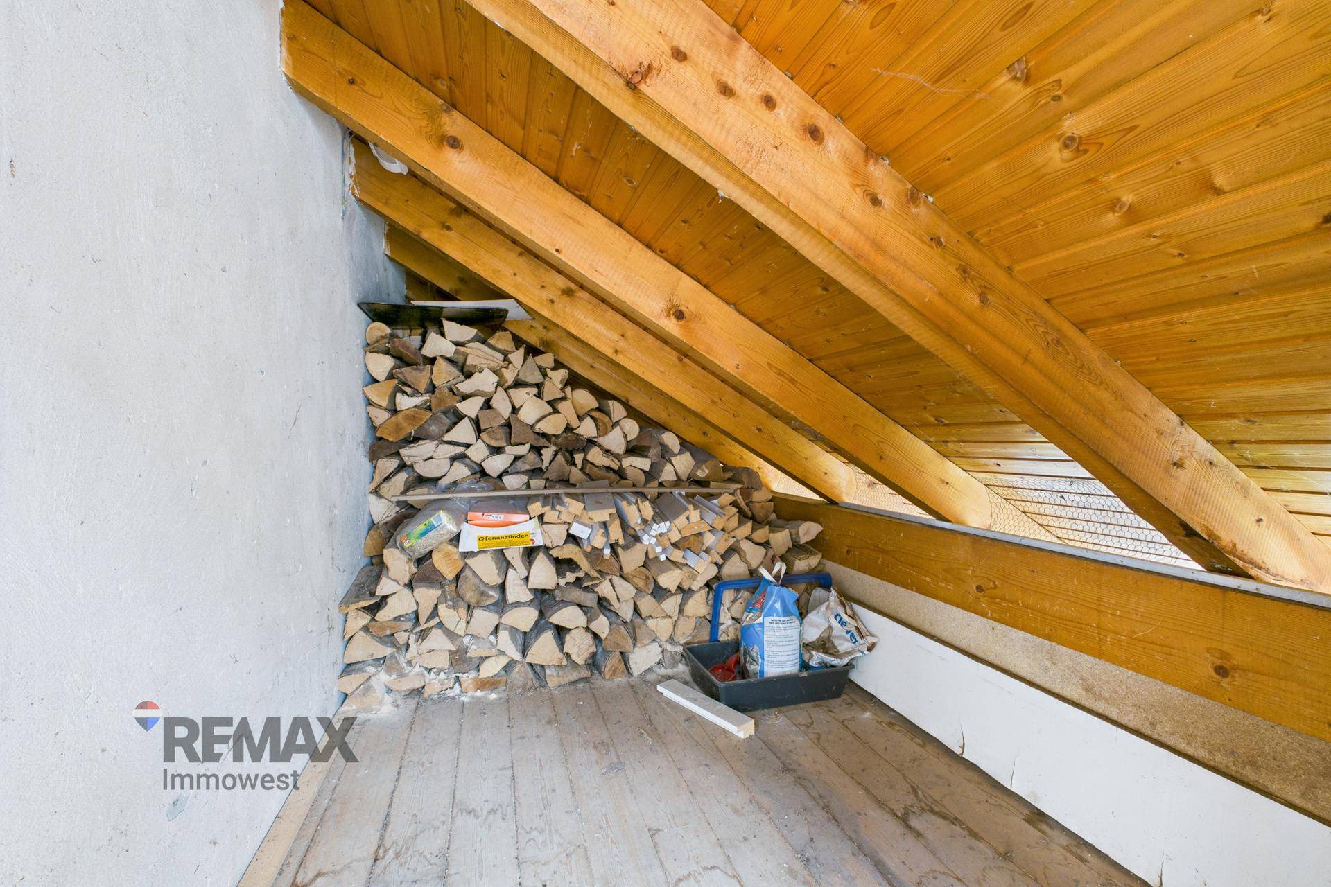 Lagerbereich unter der Dachschräge, gefüllt mit Brennholz, ideal für die kalten Monate.