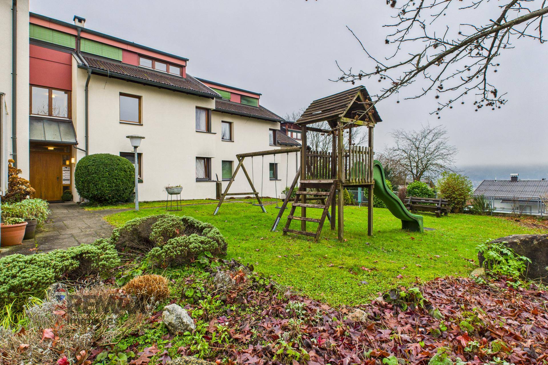 Wohnhaus mit weitläufigem Gartenbereich und Kinderspielplatz, umgeben von grüner Natur.
