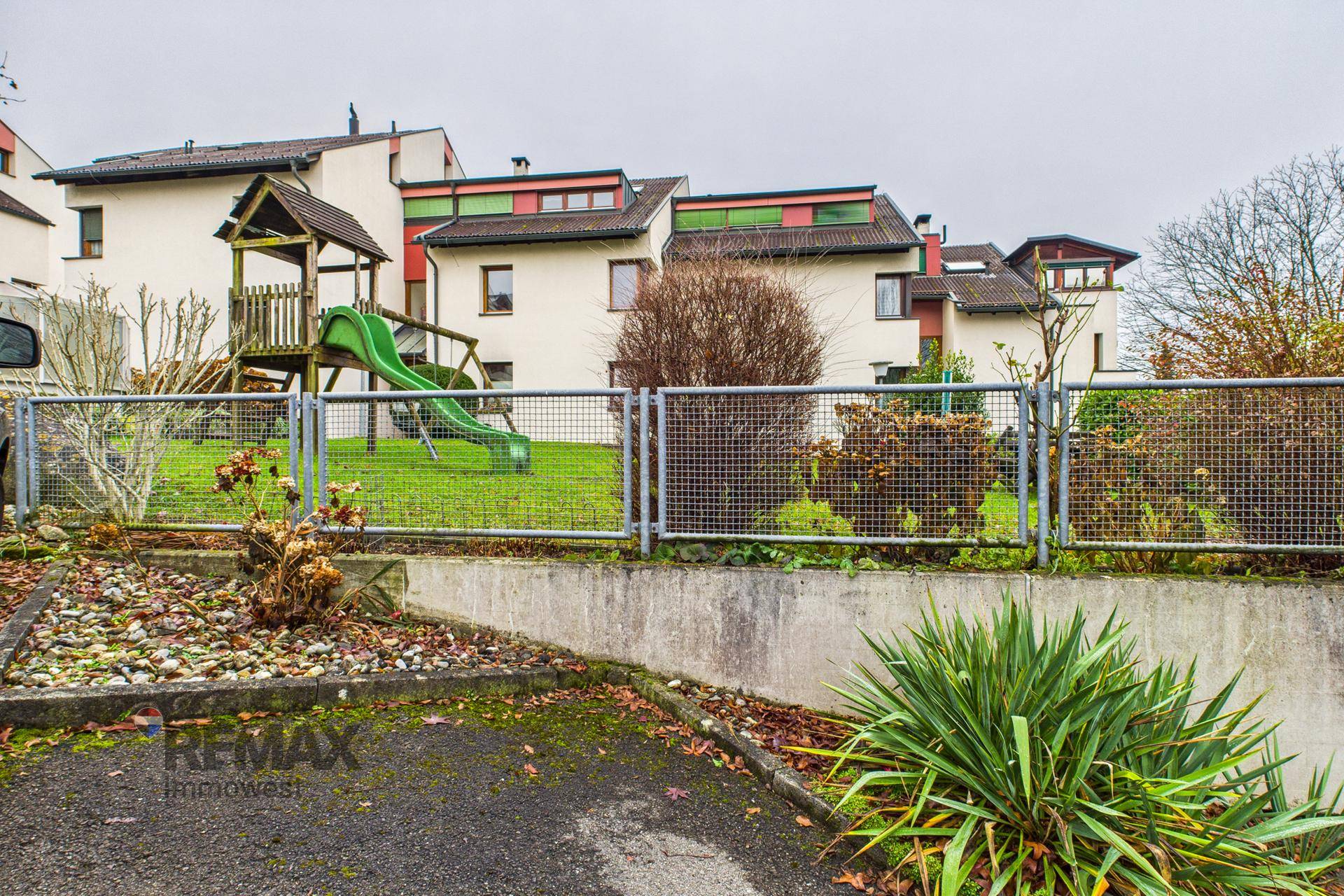 Gepflegter Gemeinschaftsgarten mit Kinderspielplatz und Blick auf die Wohngebäude.