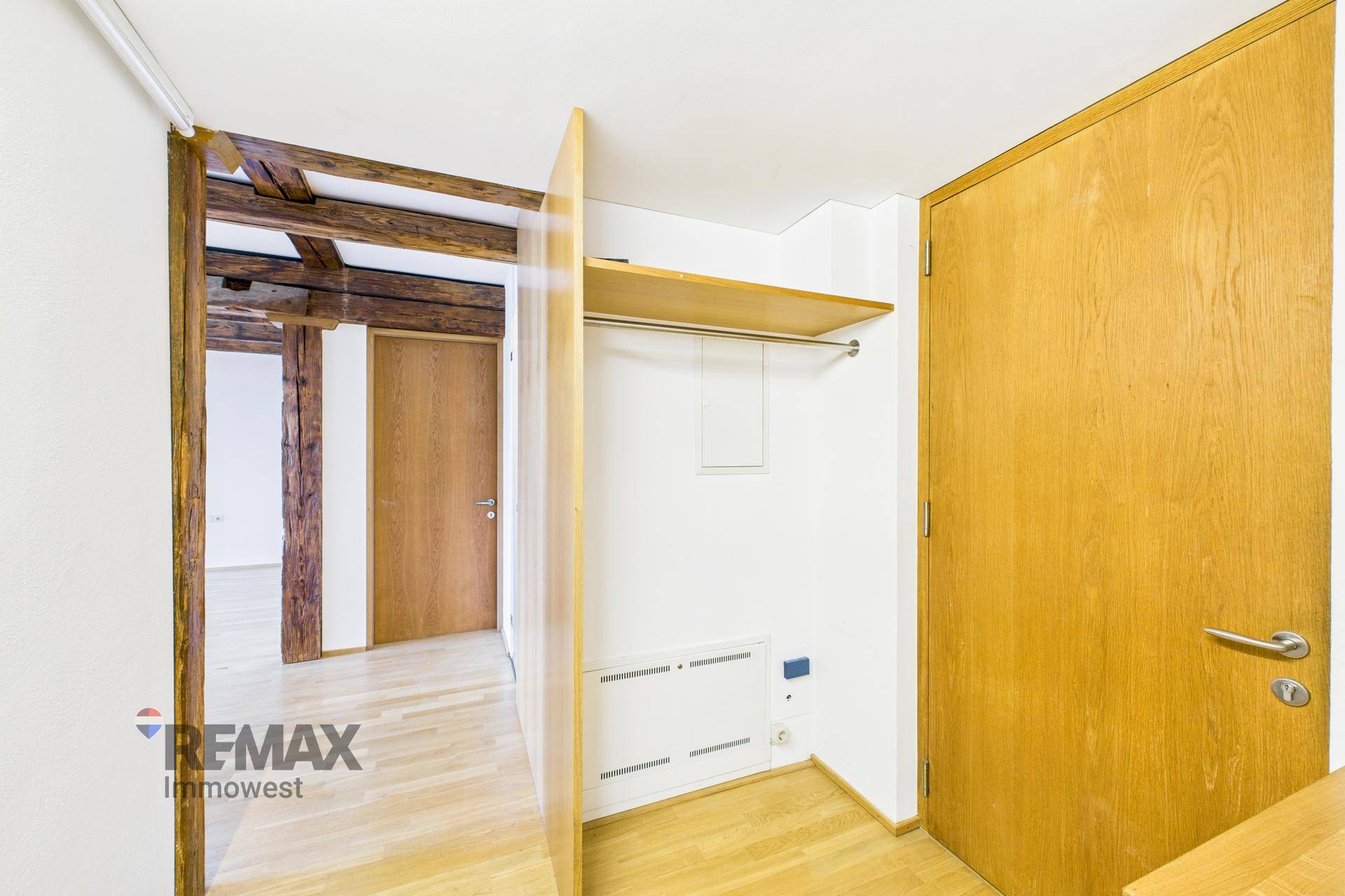 Eingangsbereich mit Garderobe und Holztüren, der zu weiteren Räumen führt.
