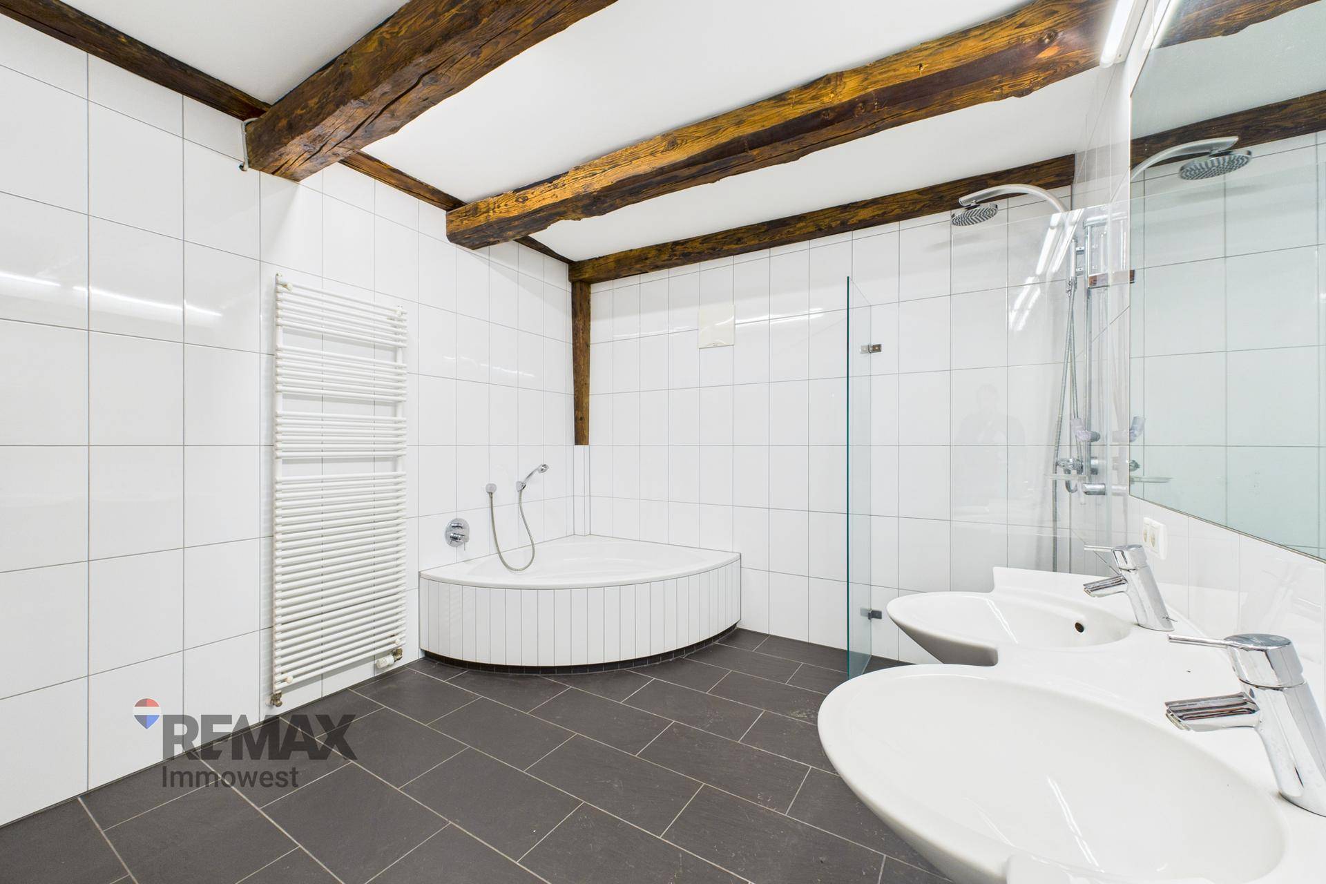 Modernes Badezimmer mit Doppelwaschbecken, Dusche, Eckbadewanne und beheiztem Handtuchhalter.