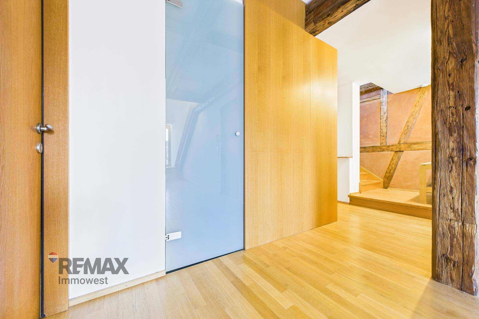 Heller Flur mit Holzboden, Holzwänden und einer modernen Glastür.