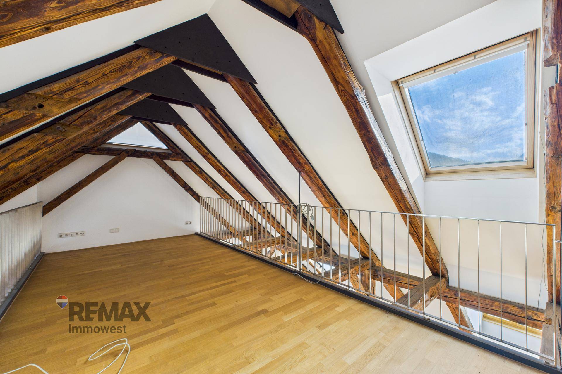 Offene Galerie im Dachgeschoss mit Holzboden, Metallgeländer und Blick auf die untere Ebene.