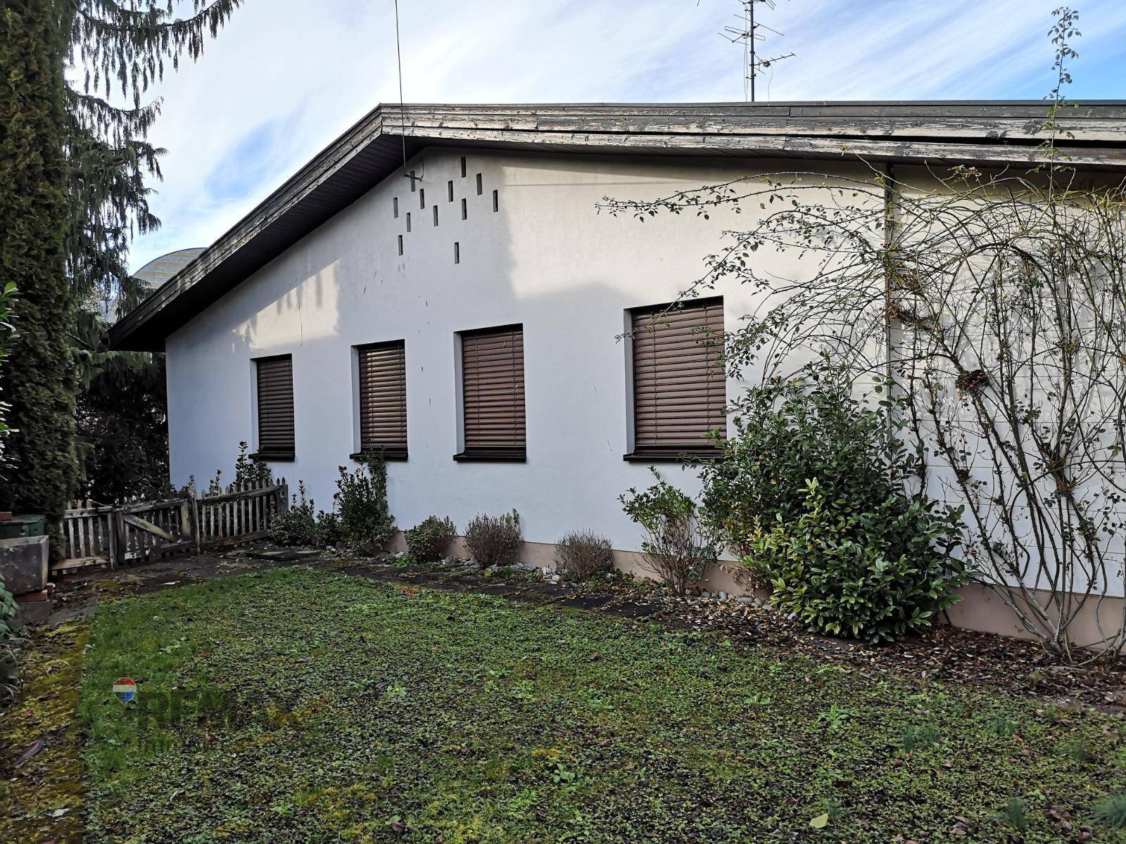 Seitenansicht des Hauses mit Fenstern, Rollläden und einem kleinen Gartenbereich.