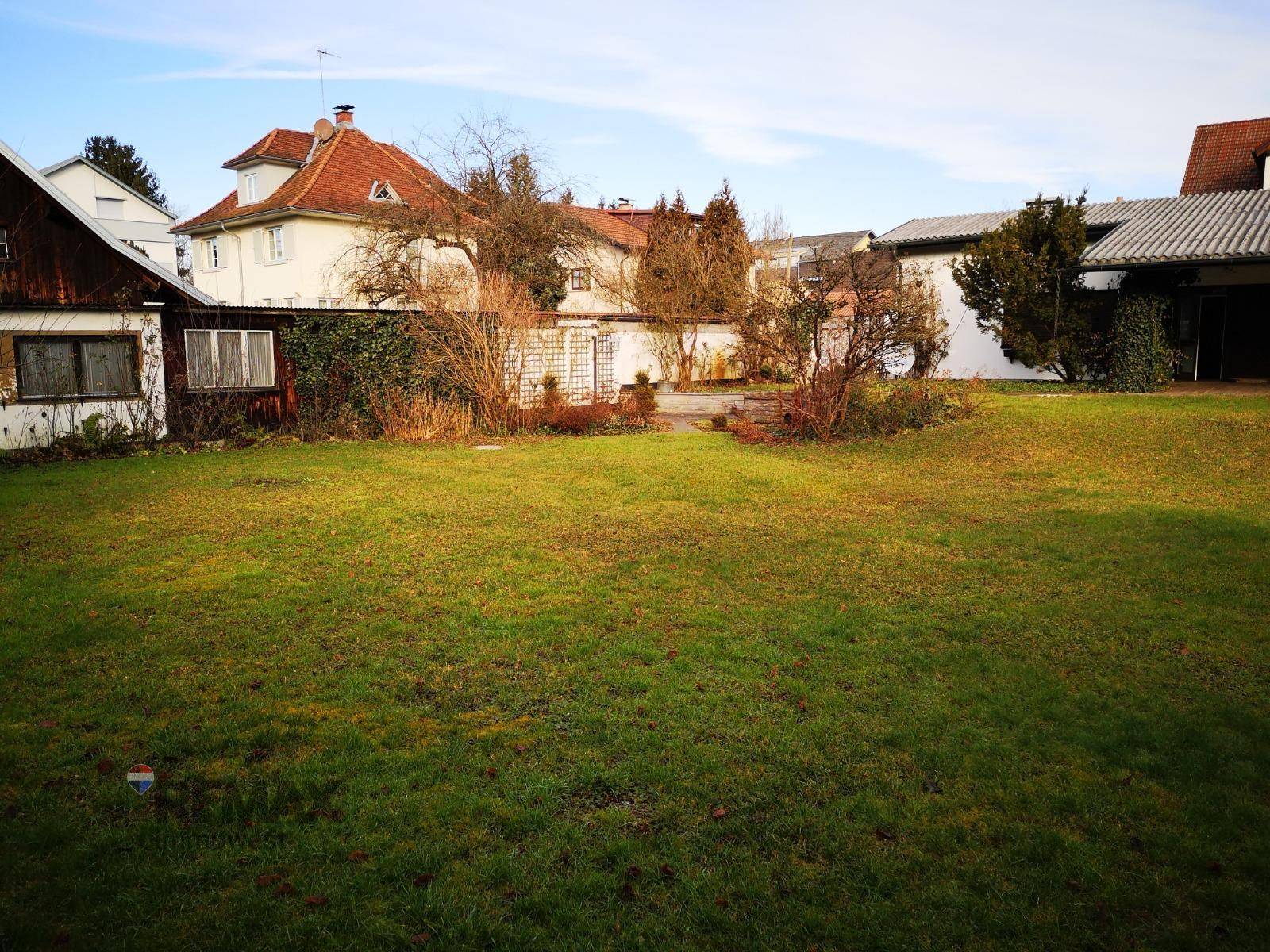 Große Rasenfläche im Garten mit Blick auf das Haus und die Nachbarschaft.