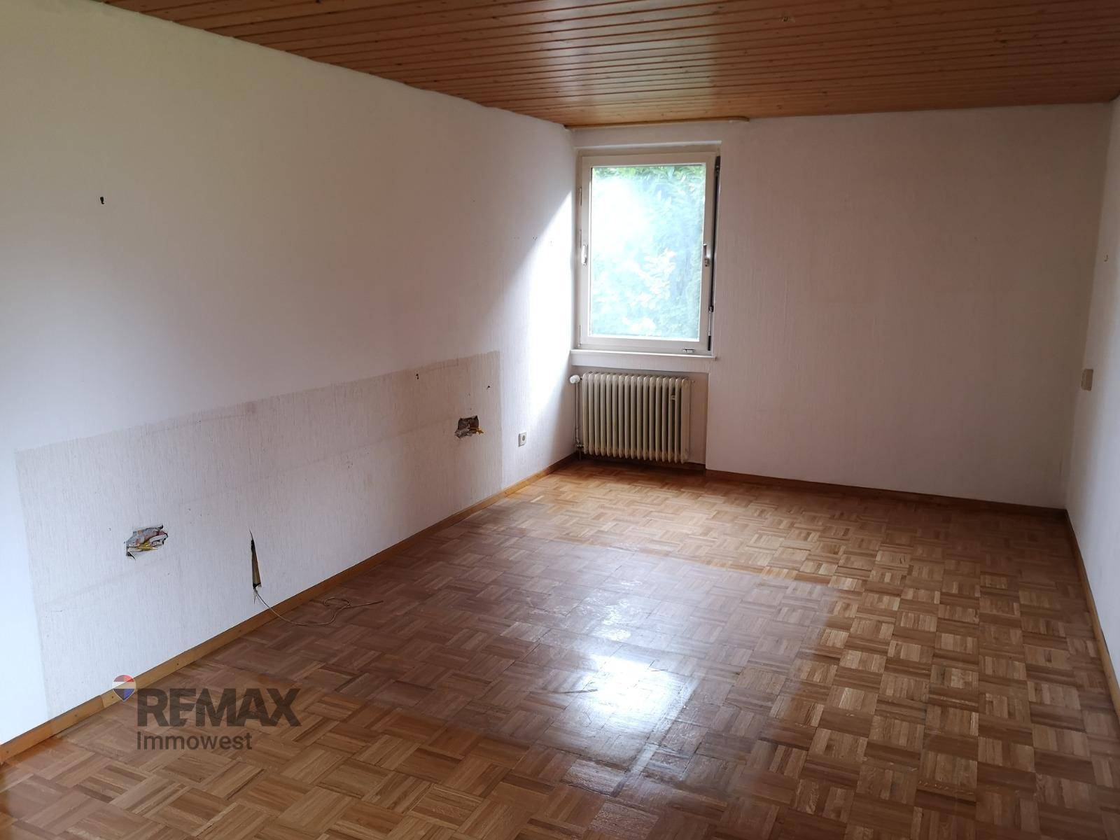 Geräumiges Zimmer mit Parkettboden, Holzdecke und Fenster.