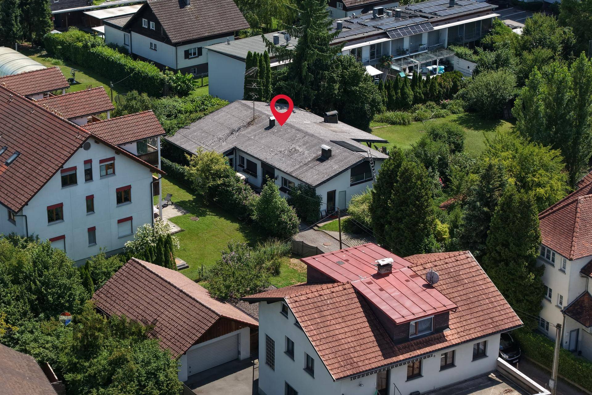 Vogelperspektive des Hauses mit rotem Standortmarker und umliegender grüner Landschaft.