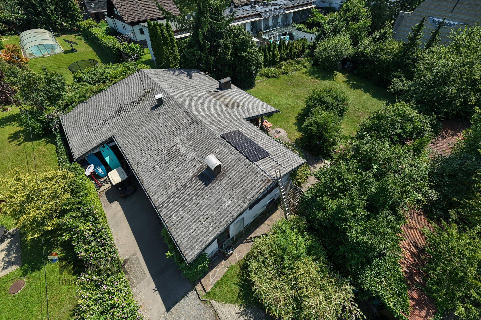 Dachansicht des Hauses mit Photovoltaikanlage und umliegendem Gartenbereich.