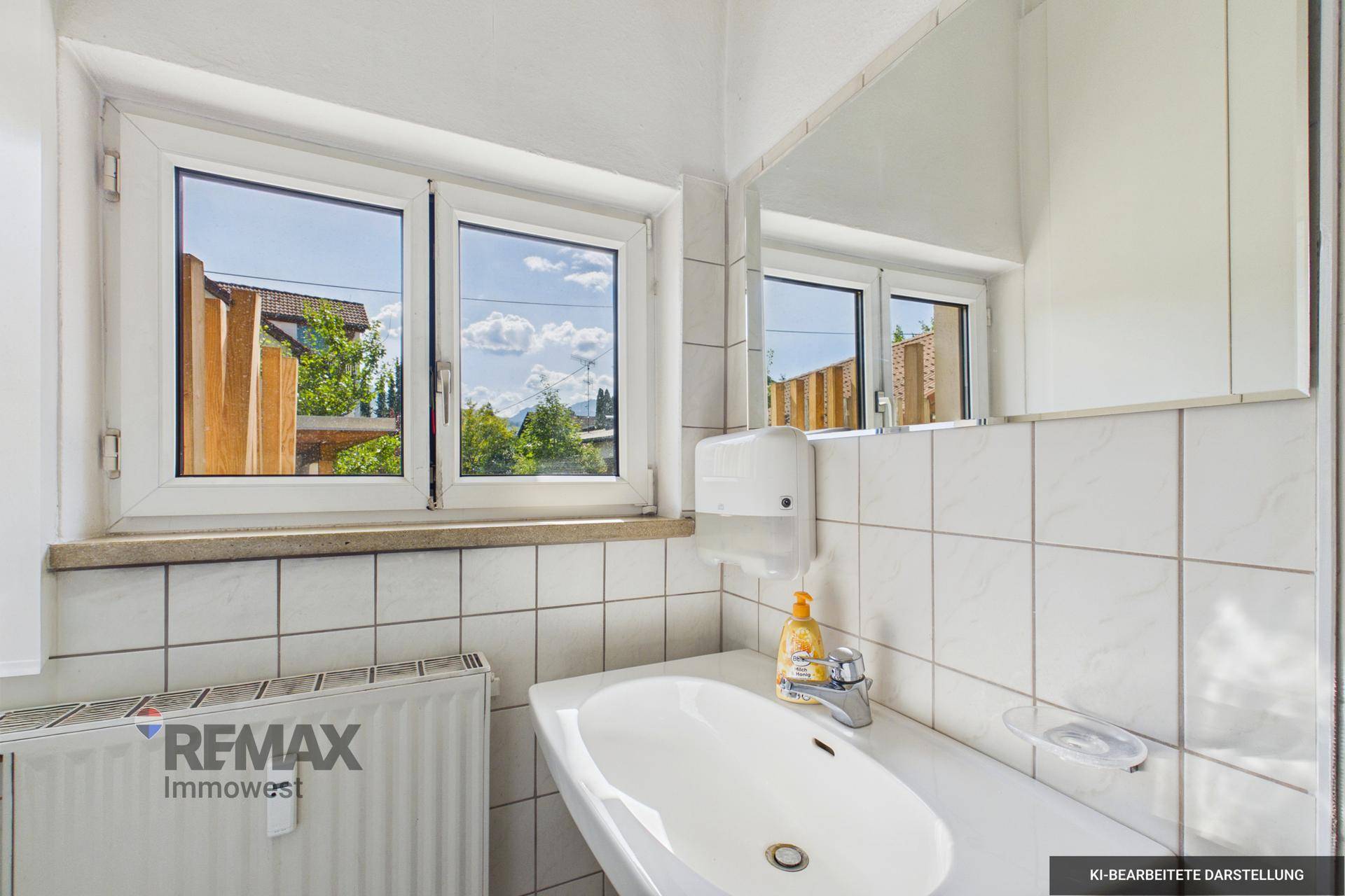 Kleines Badezimmer mit Waschbecken, Spiegel und Fenster, hell gefliest.
