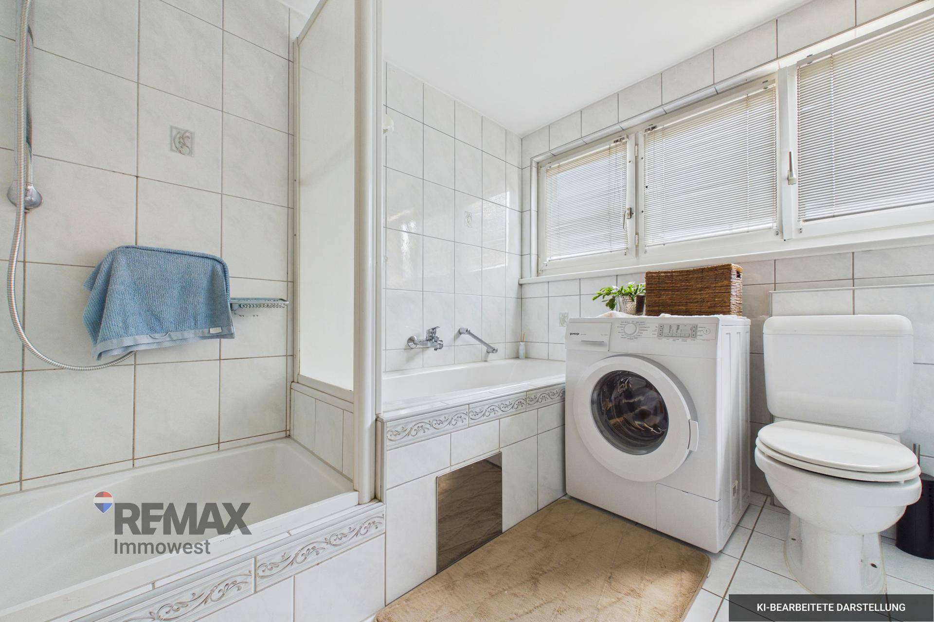 Badezimmer mit Badewanne, Dusche, Toilette und Waschmaschine, hell gefliest und mit Fenster.