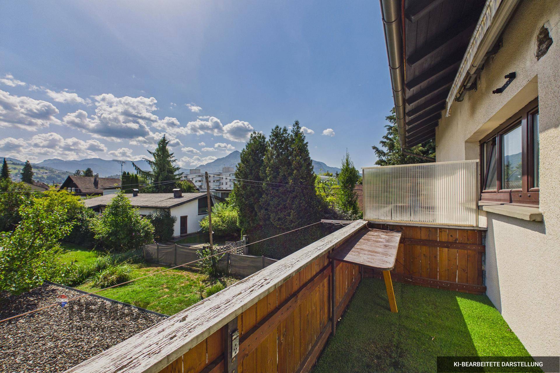 Balkon mit Kunstrasen und Holzgeländer, bietet einen weiten Blick auf die Berge und Umgebung.