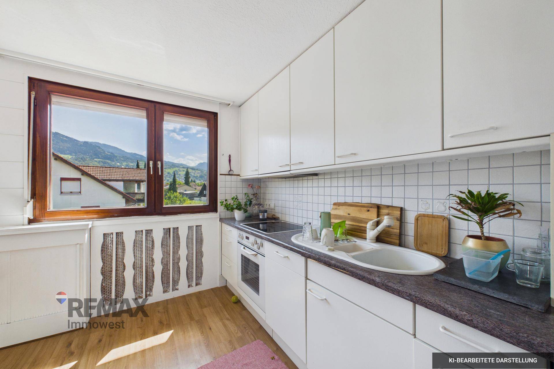 Traditionelle Küche mit weißen Schränken, dunkler Arbeitsplatte und einem Fenster mit Bergblick.