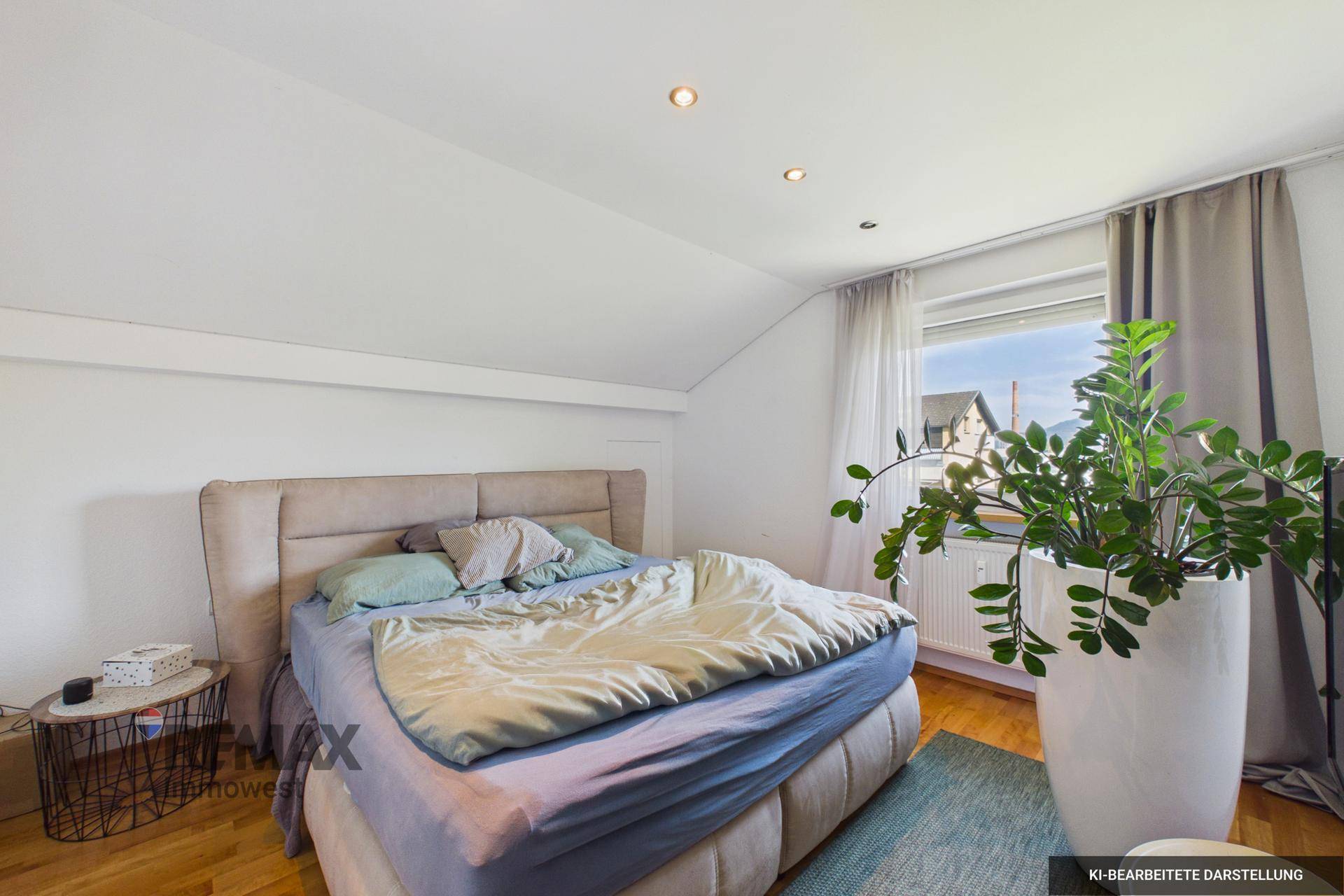 Helles Schlafzimmer mit Dachschräge, Holzboden und einem großen Bett.