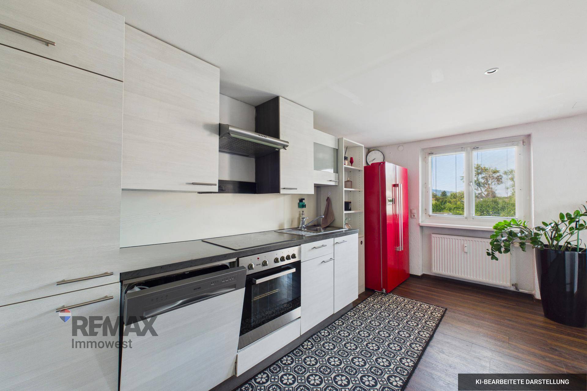 Moderne Küche mit weißen Schränken, dunkler Arbeitsplatte und einem auffälligen roten Kühlschrank.