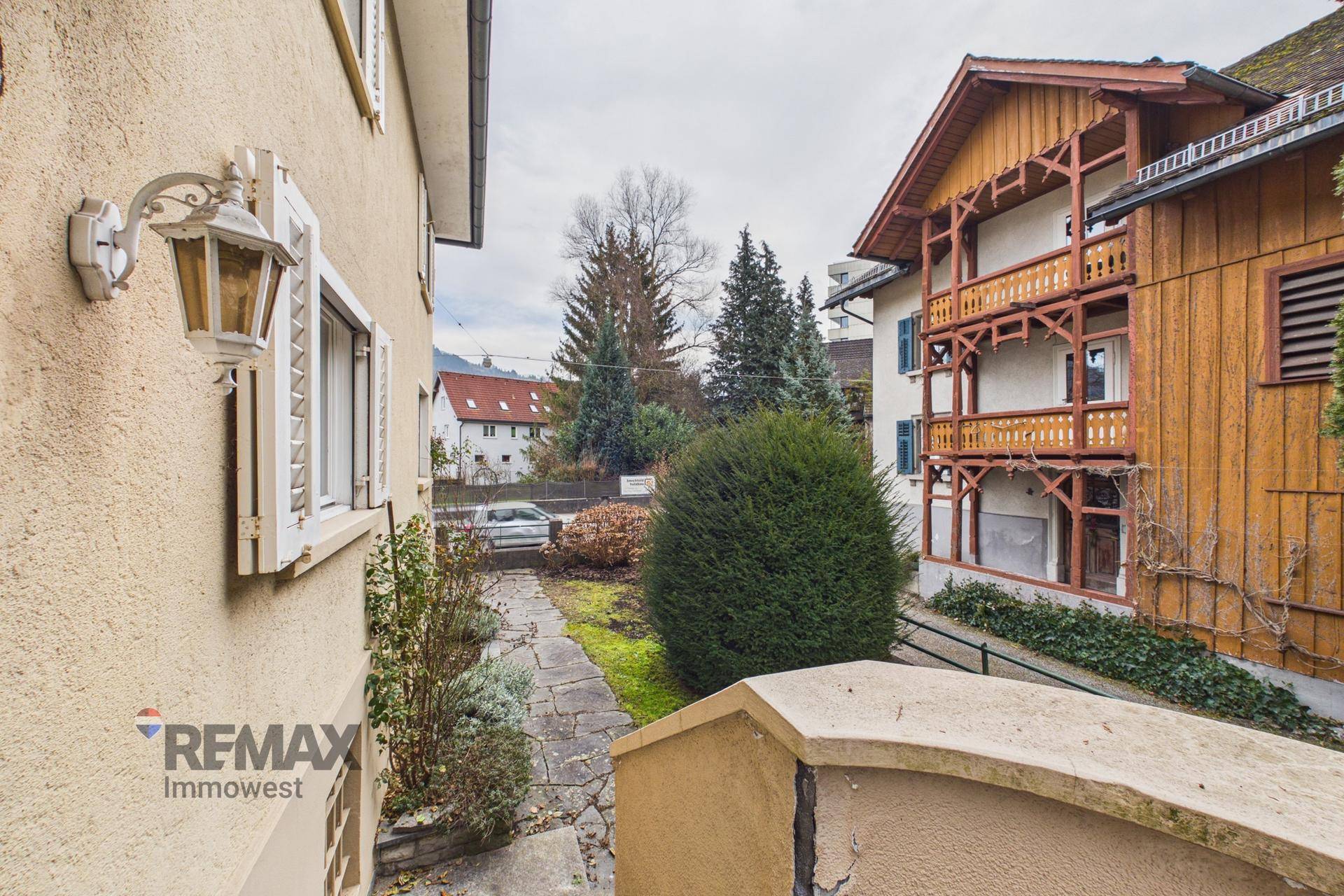 Seitenansicht des Gebäudes mit Gartenweg und Blick auf die Nachbarschaft.