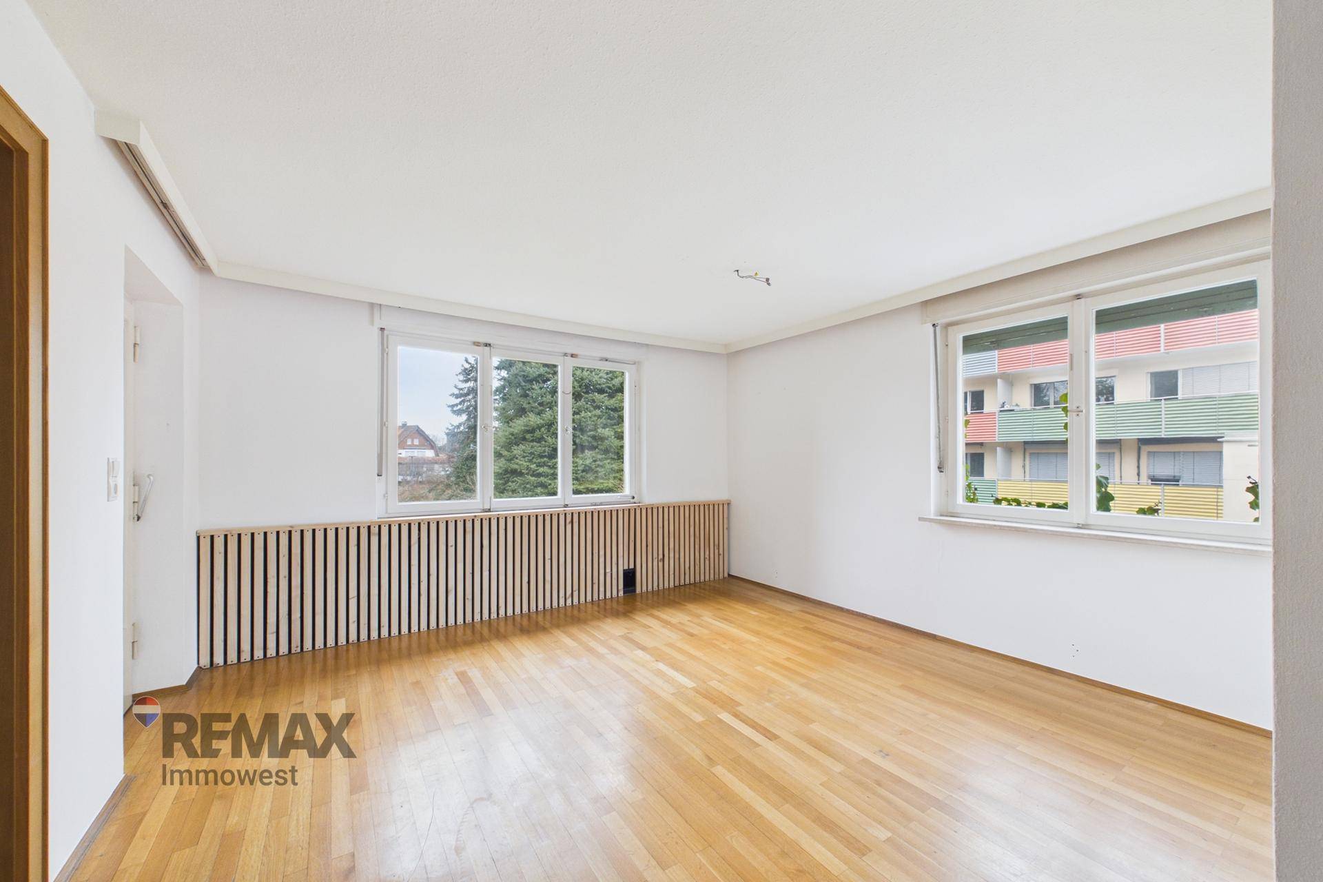 Geräumiges Schlafzimmer mit Parkettboden und großen Fenstern, die viel Licht hereinlassen.