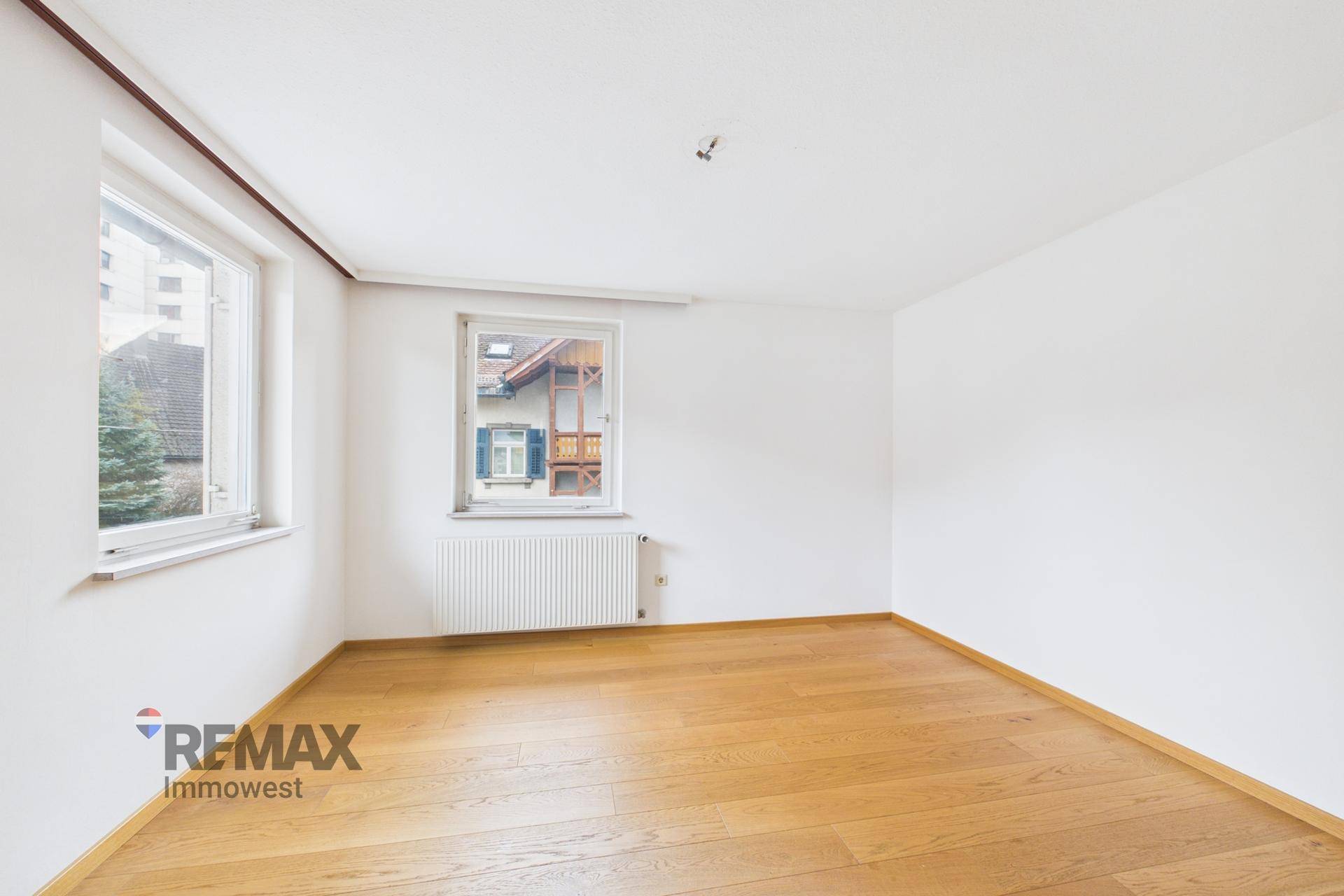 Geräumiges Schlafzimmer mit Parkettboden und zwei Fenstern, die viel Licht spenden.