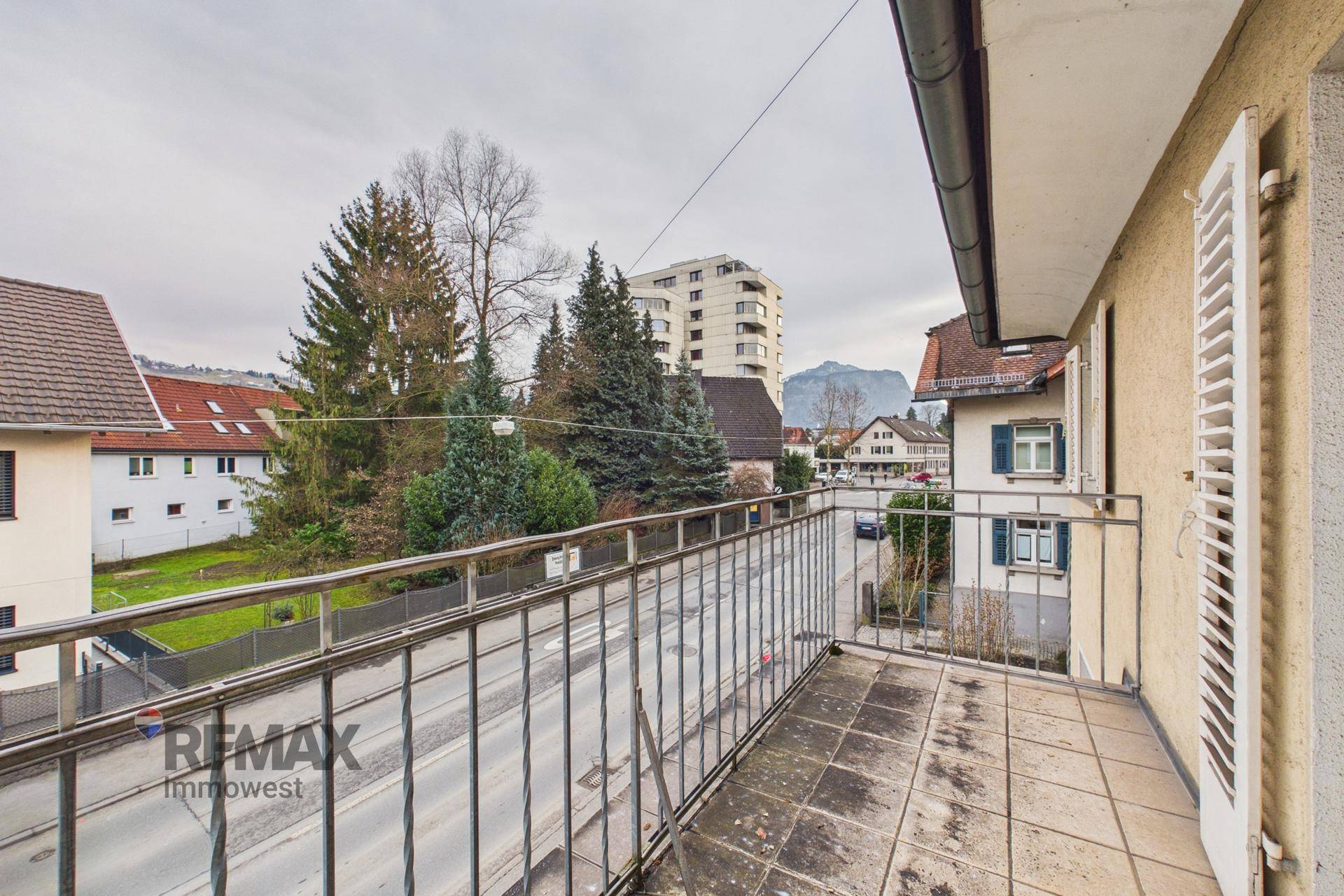 Balkon mit Metallgeländer und Fliesenboden, Blick auf die Straße und Berge.