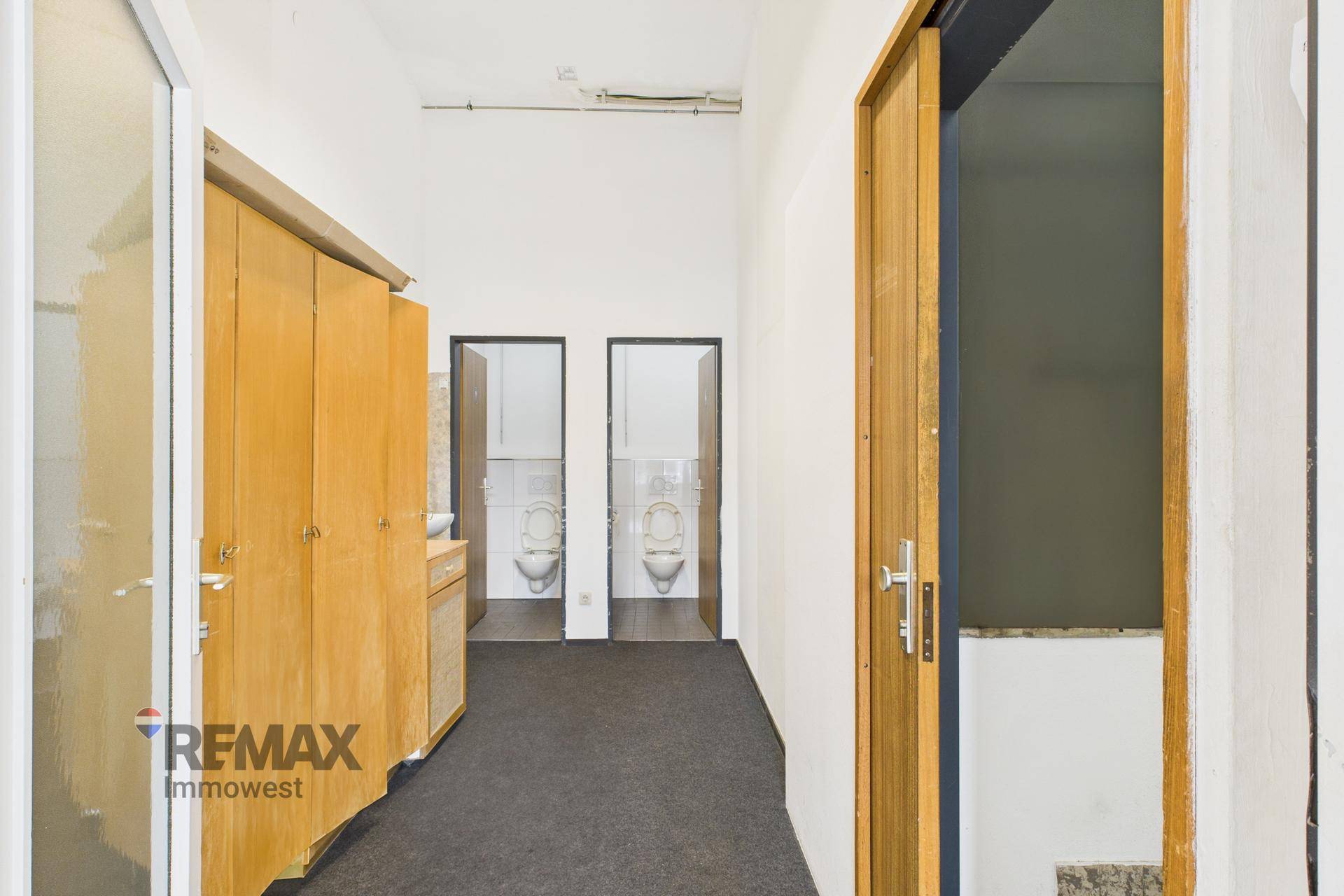 Flur mit Holzschränken und Zugang zu zwei Toilettenräumen.
