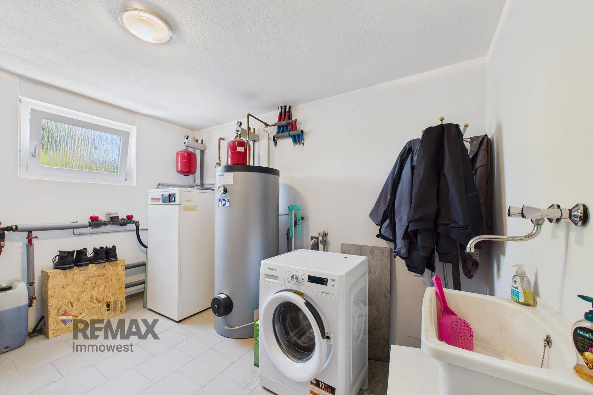 Hauswirtschaftsraum mit Waschmaschine, Warmwasserboiler und Heizungsanlage.