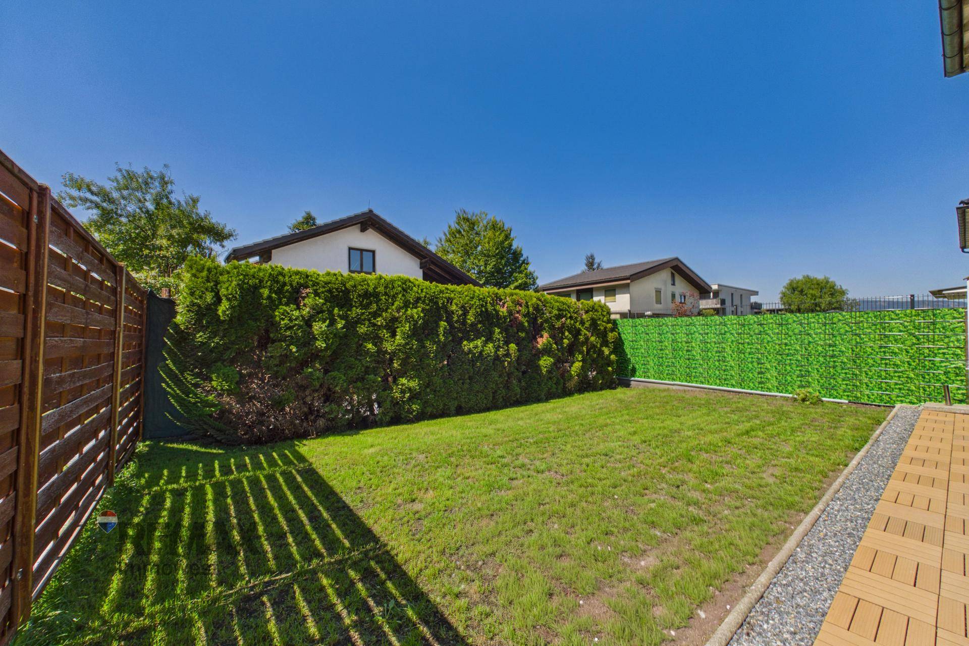 Gepflegter Garten mit Rasenfläche, hohen Hecken und Holzzaun für Privatsphäre.