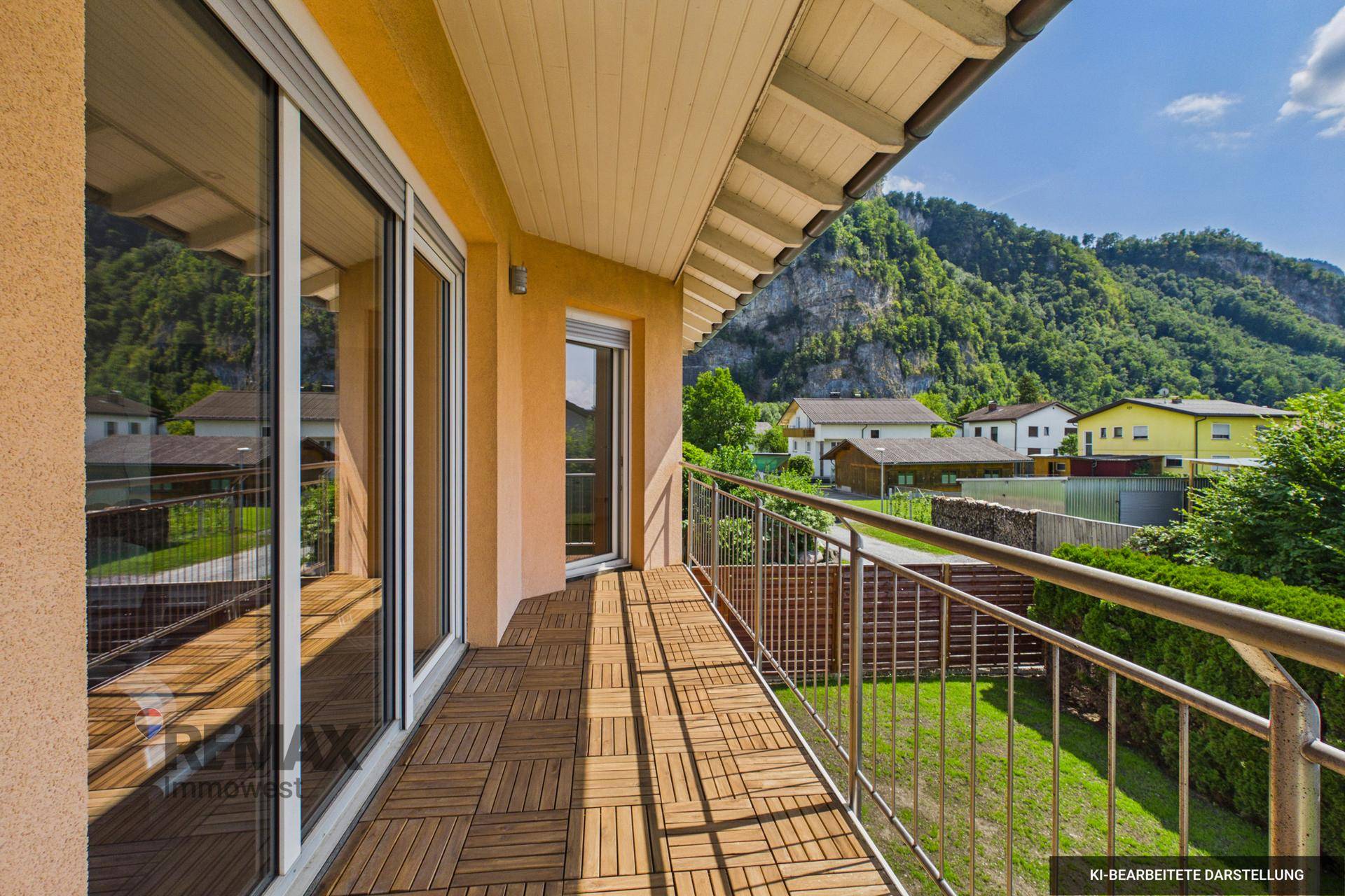 Geräumiger Balkon mit Holzboden, Edelstahlgeländer und weitem Blick auf die Berge.