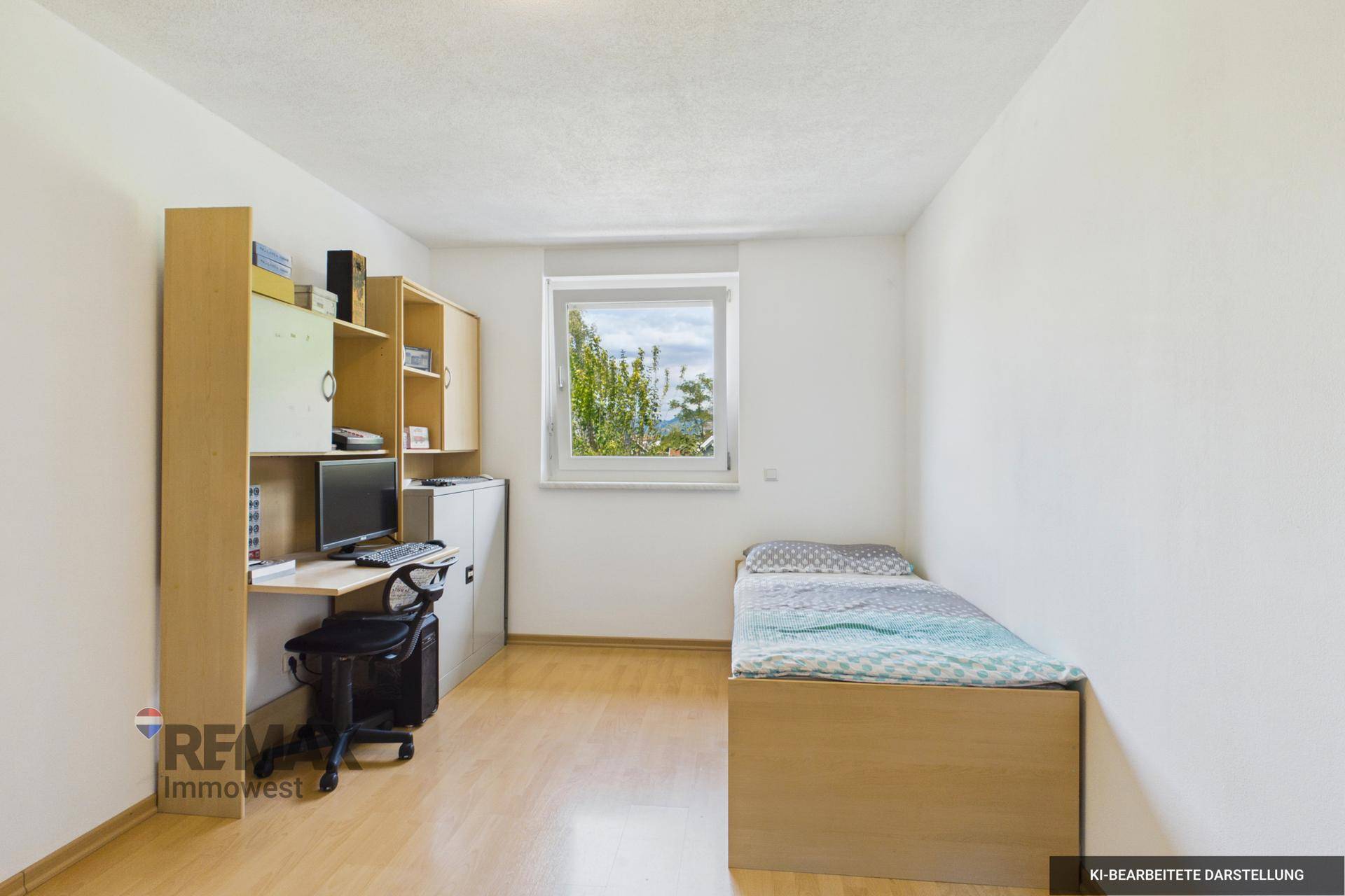 Helles Zimmer mit Einzelbett, Schreibtisch und Fenster mit Blick ins Grüne.