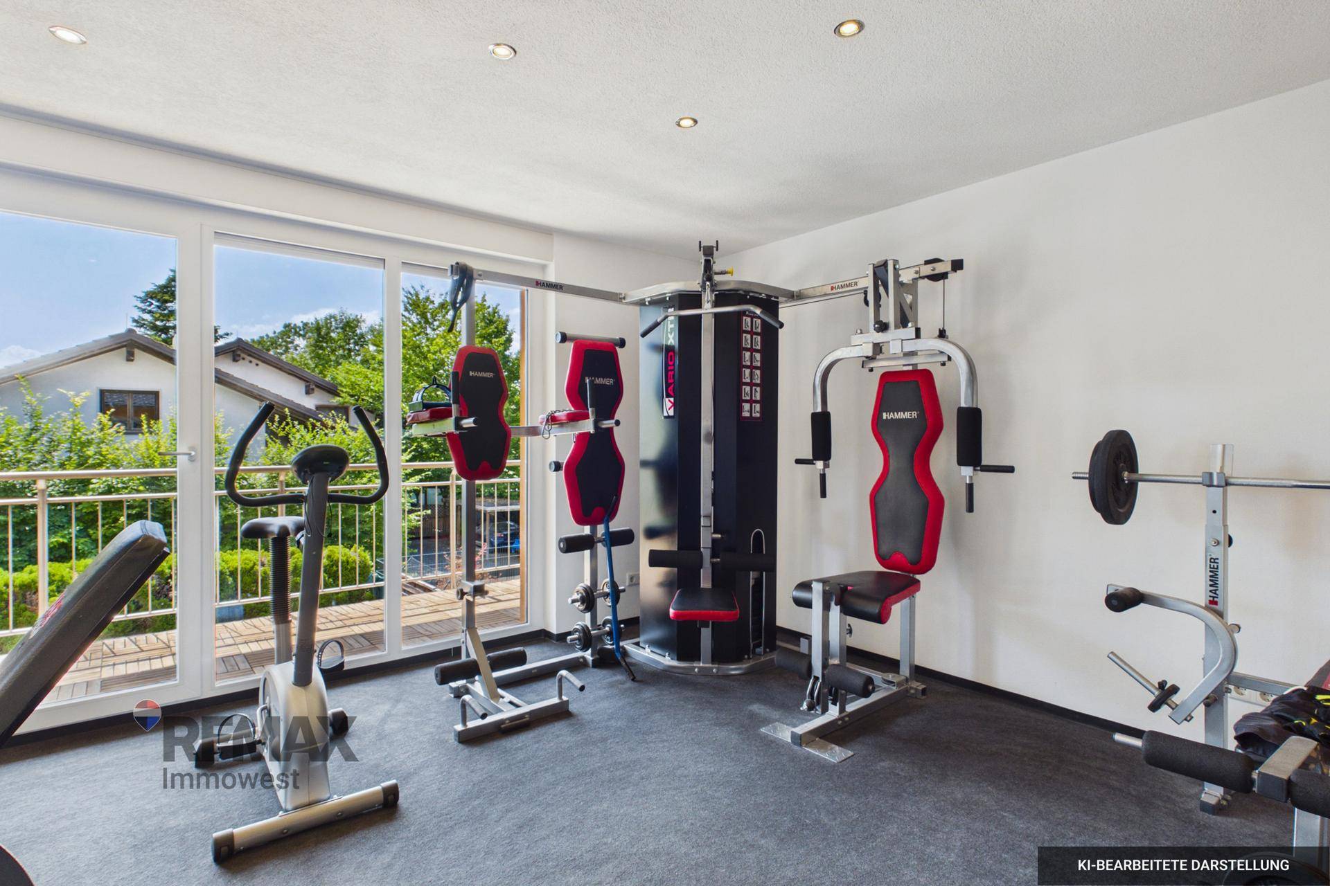 Fitnessraum mit verschiedenen Trainingsgeräten, großen Fenstern und Zugang zum Balkon.