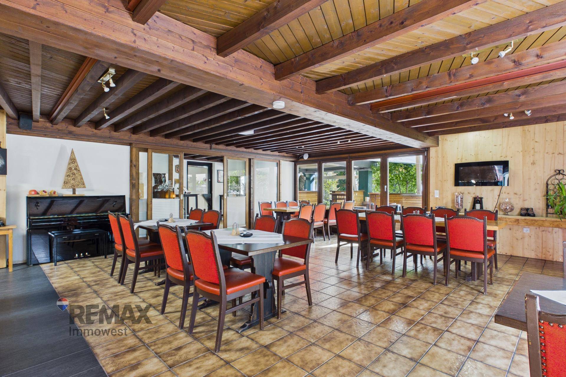 Großer Speisesaal mit Holzbalkendecke, vielen Tischen und roten Stühlen, ideal für größere Gruppen.