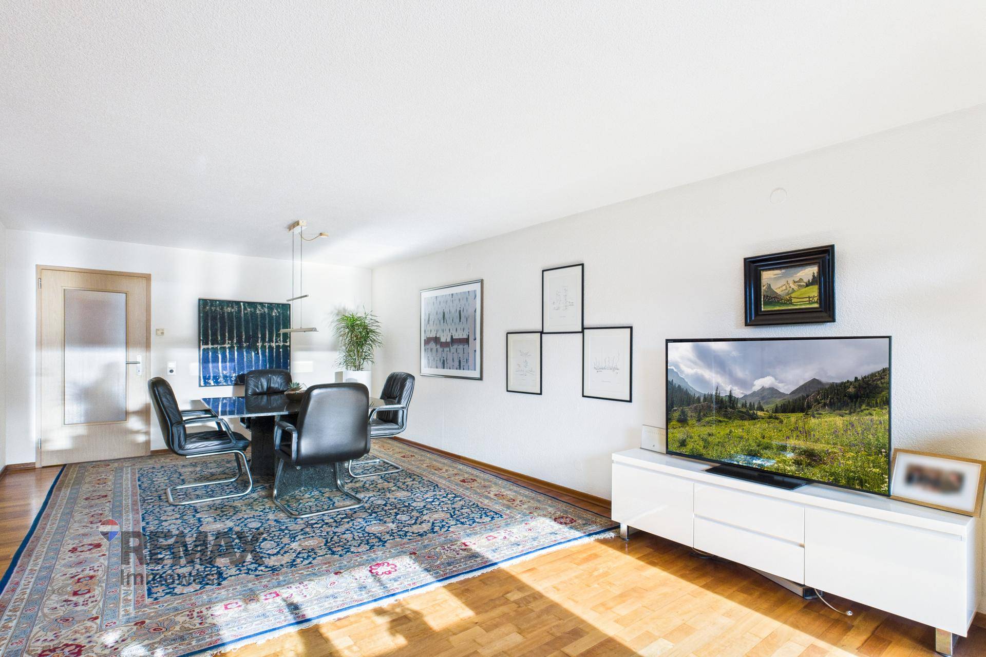 Geräumiger Wohn- und Essbereich mit Holzboden, Teppich und modernem TV-Möbel.