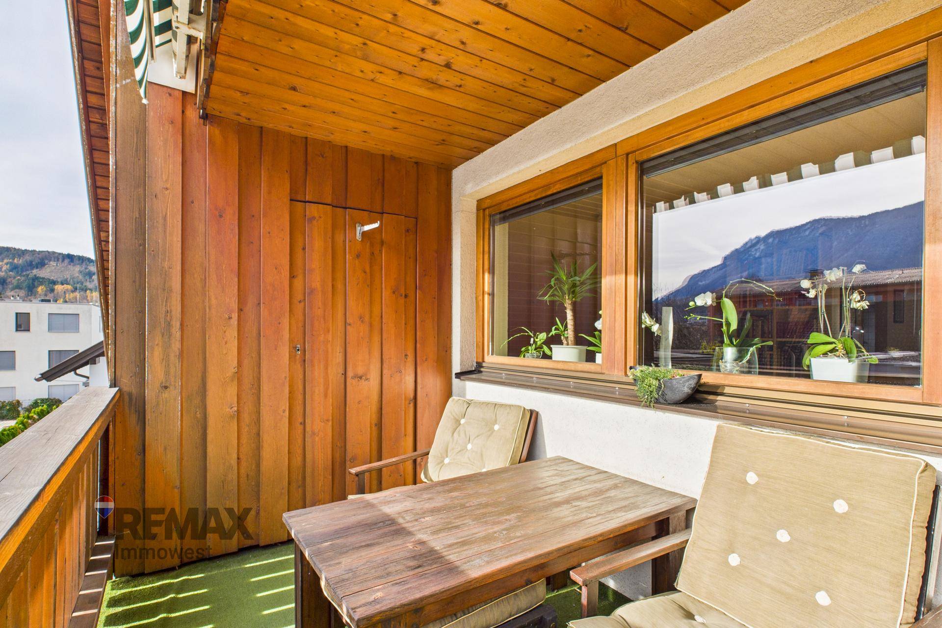 Gemütlicher Holzbalkon mit Sitzgelegenheiten und Blick auf die Umgebung.
