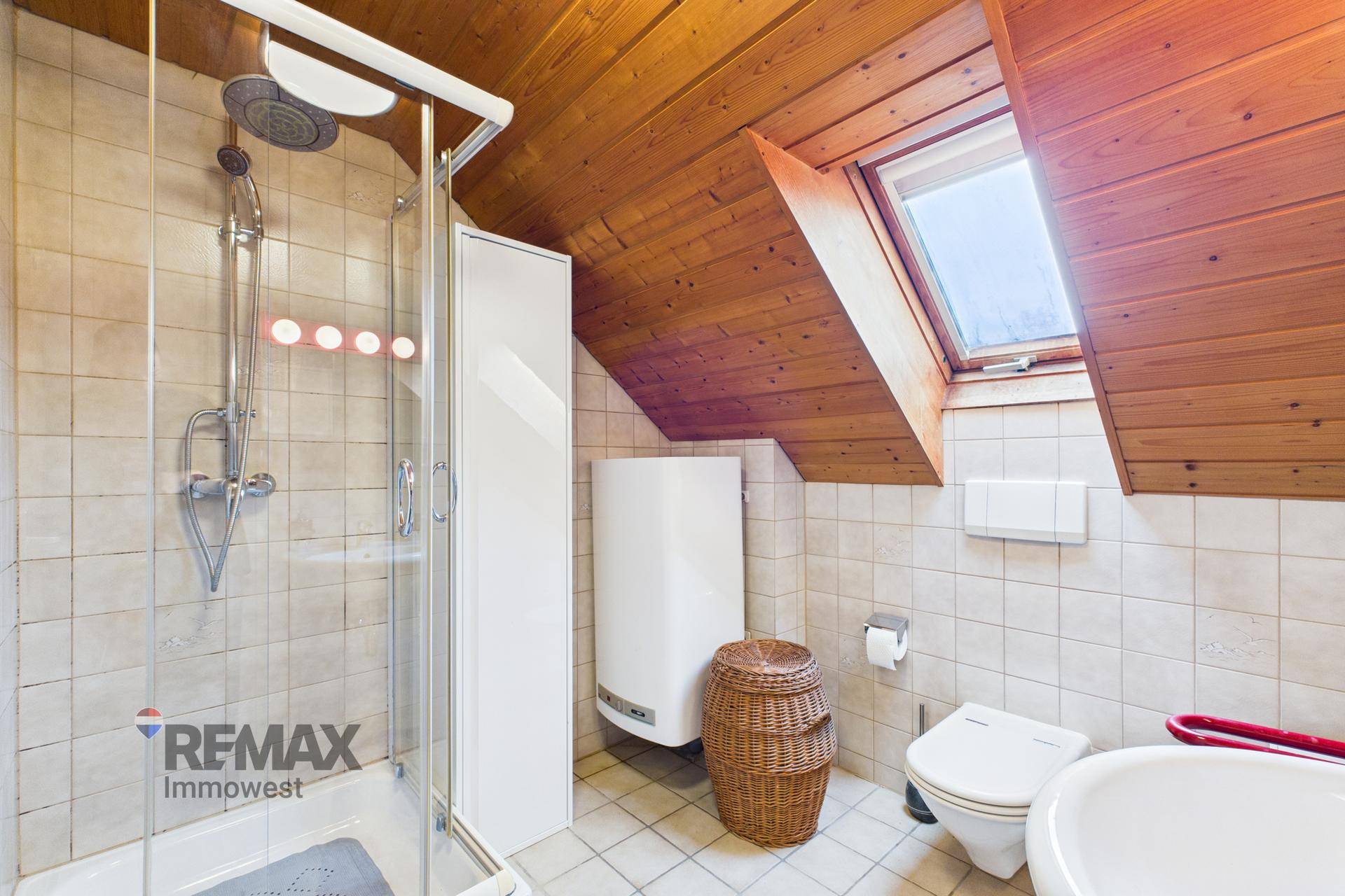 Badezimmer im Dachgeschoss mit Duschkabine, WC und Dachfenster.
