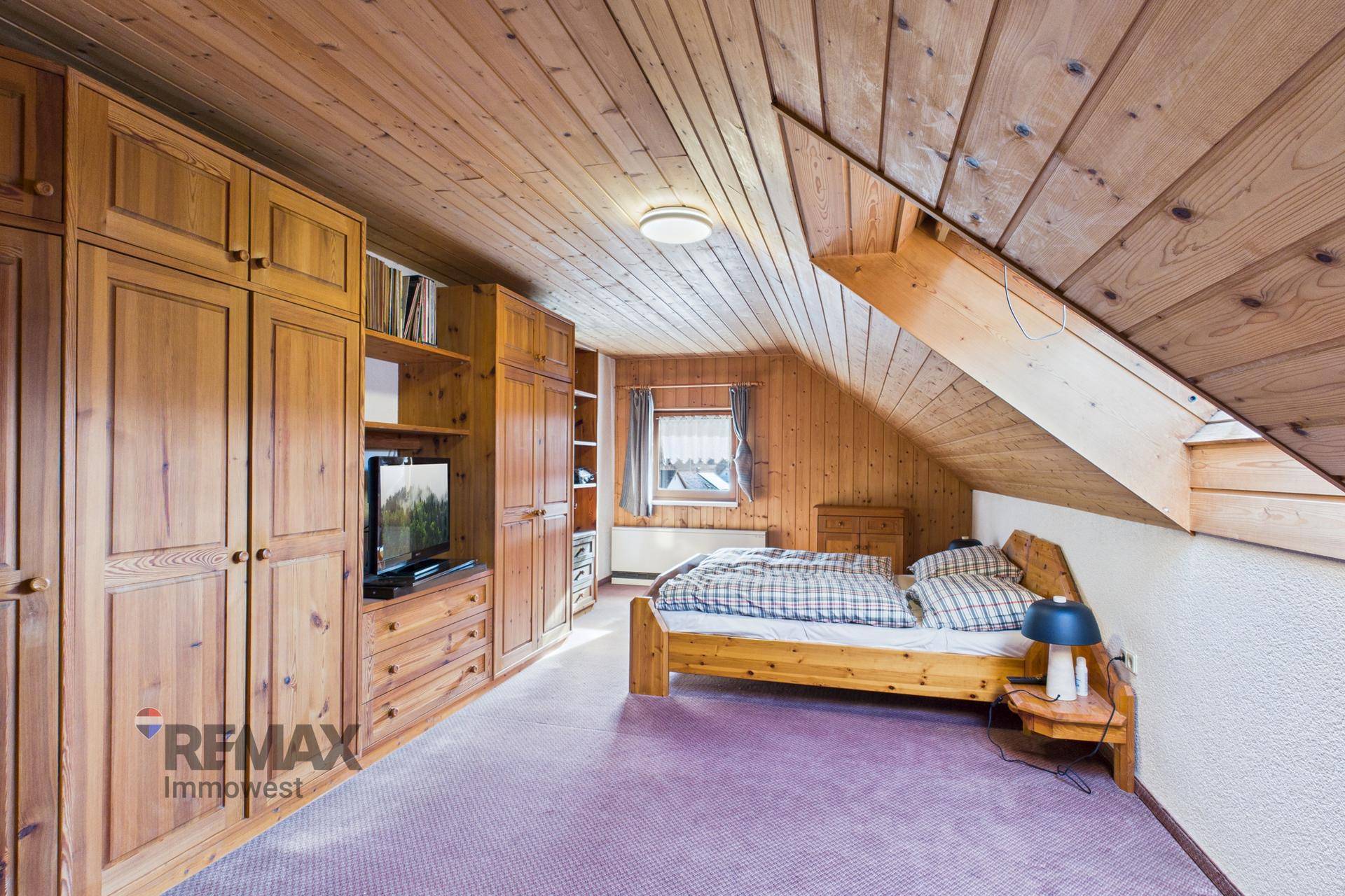 Schlafzimmer im Dachgeschoss mit Holzdecke, Einbauschränken und Teppichboden.