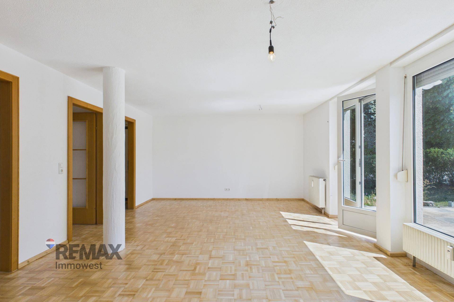 Geräumiger Wohnraum mit hellem Parkettboden und großen Fenstern für viel Tageslicht.