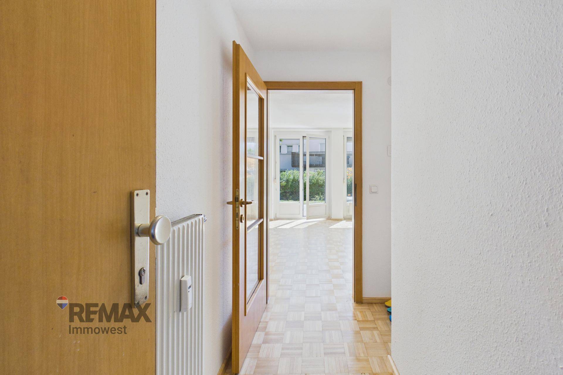 Heller Flur mit Parkettboden und Holztüren, der zum Wohnbereich führt.