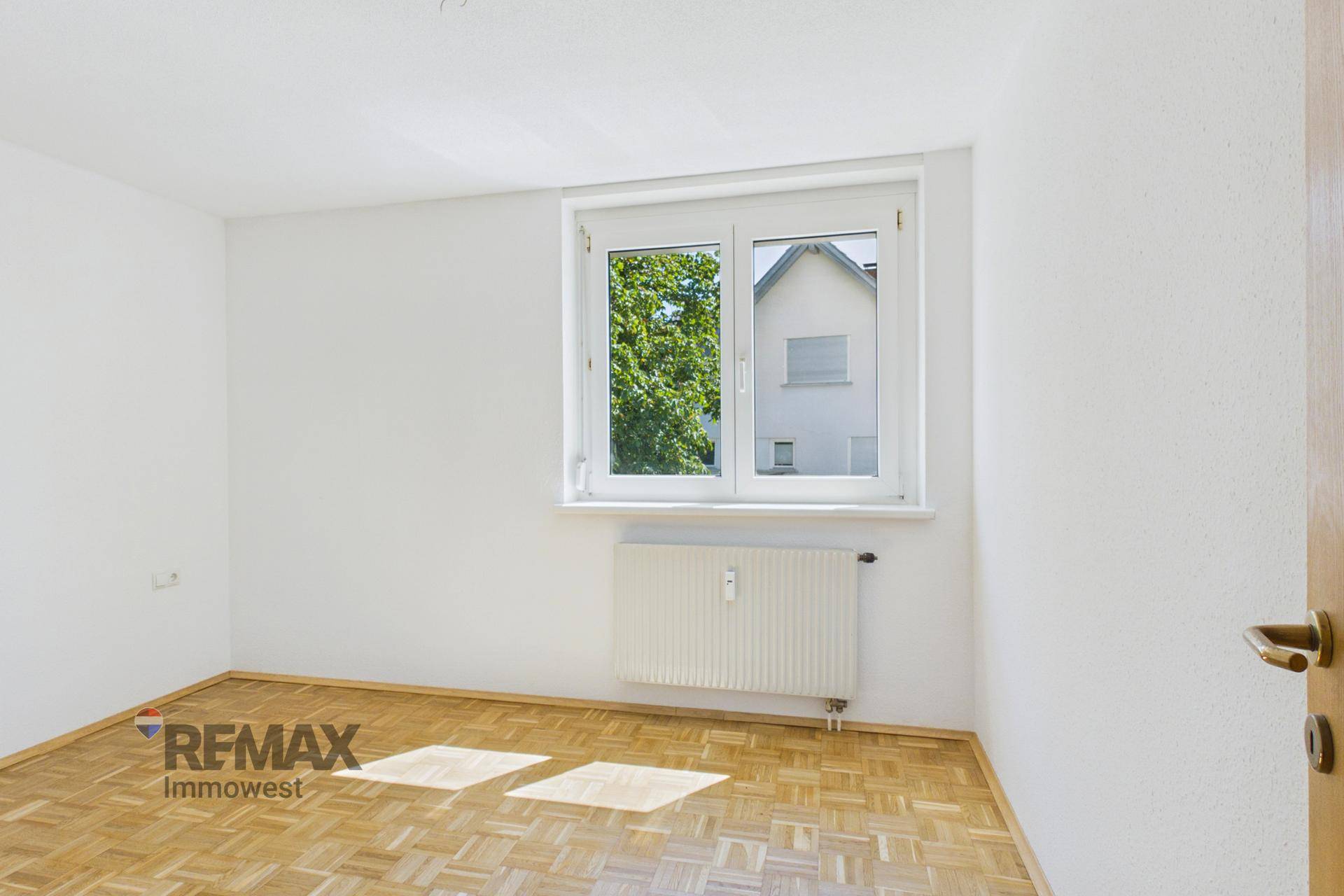 Geräumiges Schlafzimmer mit Parkettboden und großem Fenster für viel Tageslicht.