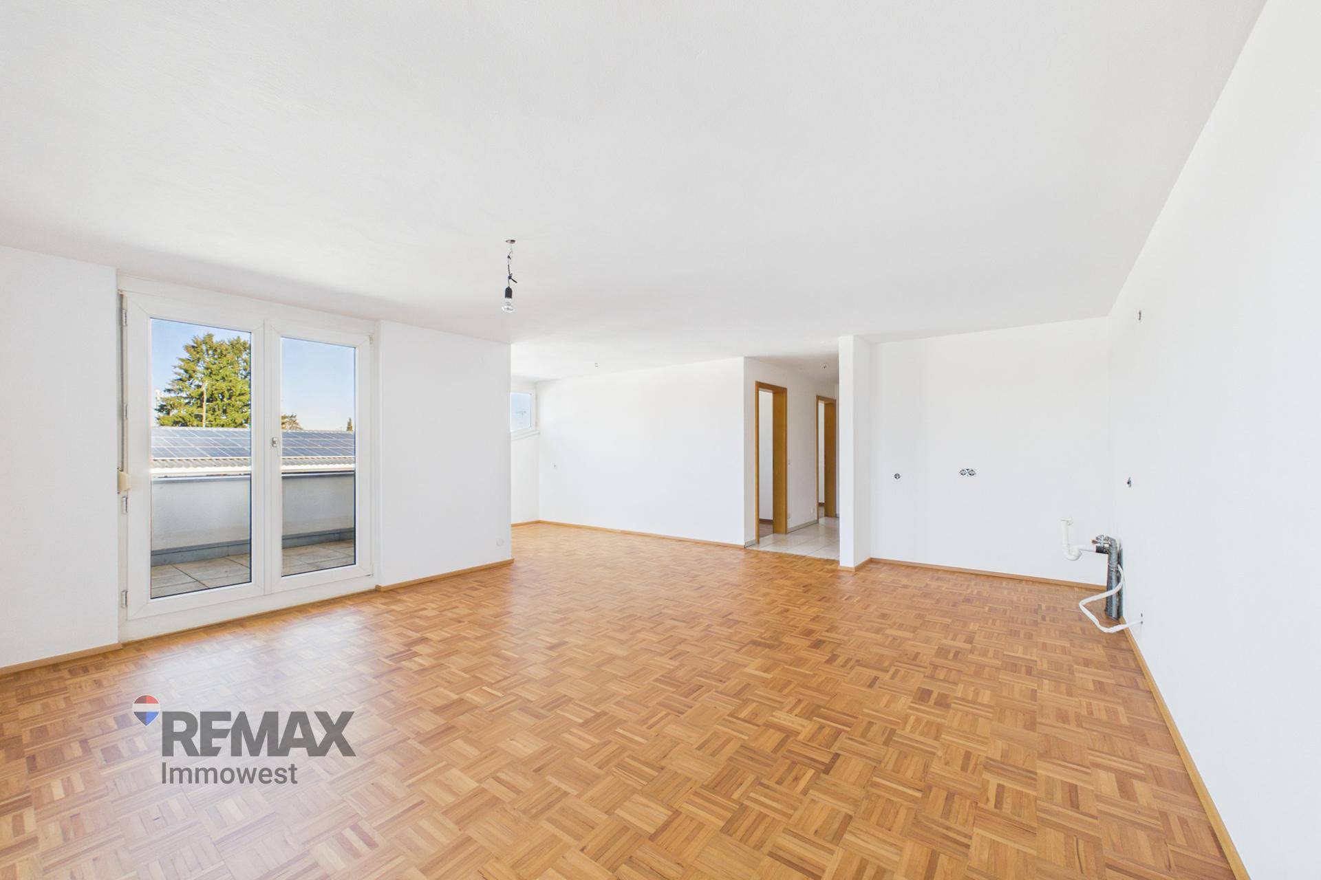 Heller, unmöblierter Wohnbereich mit Parkettboden und Zugang zu einem weiteren Balkon.