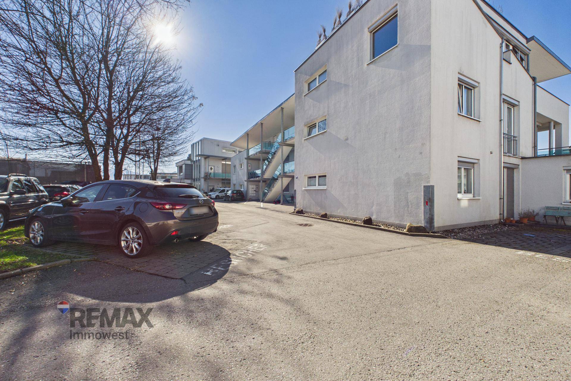 Seitenansicht des Gebäudes mit Parkplätzen und sonniger Umgebung an einem klaren Tag.