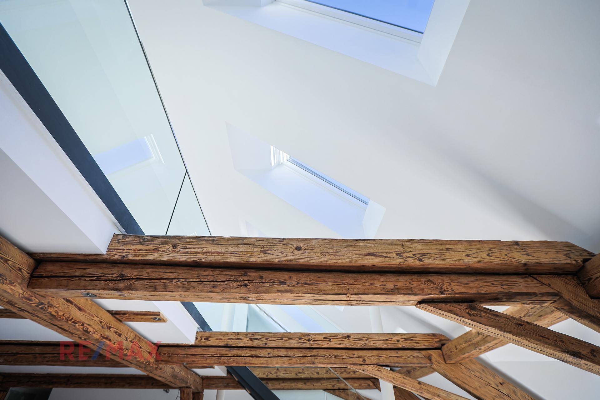 Heller Dachboden mit freiliegenden Holzbalken und modernen Dachfenstern, die viel natürliches Licht hereinlassen.